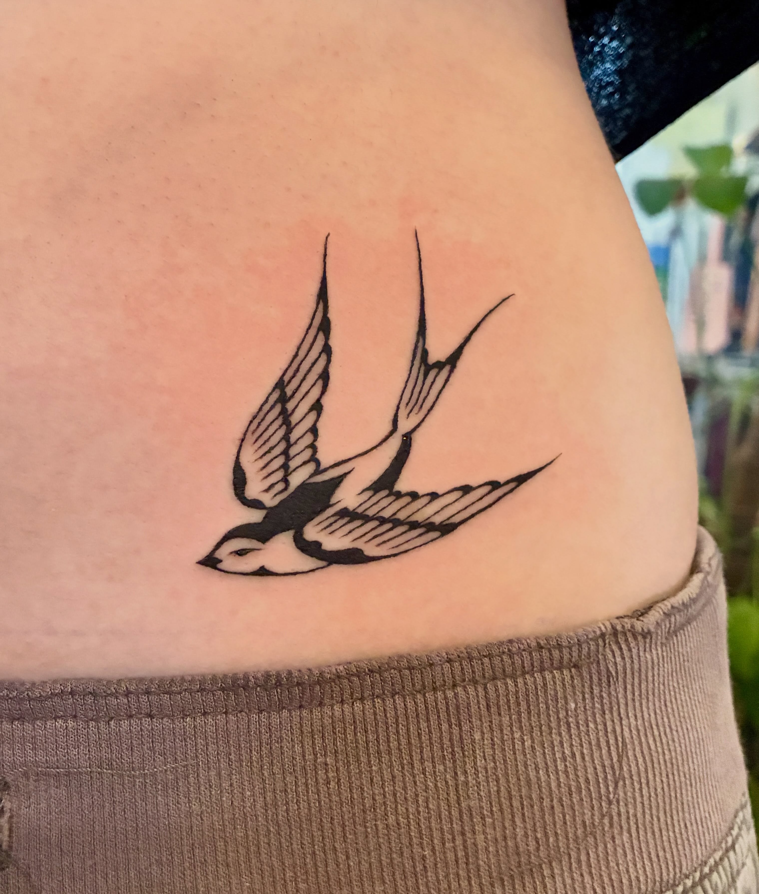 Swallow black and grey tattoo on the upper arm by thalia