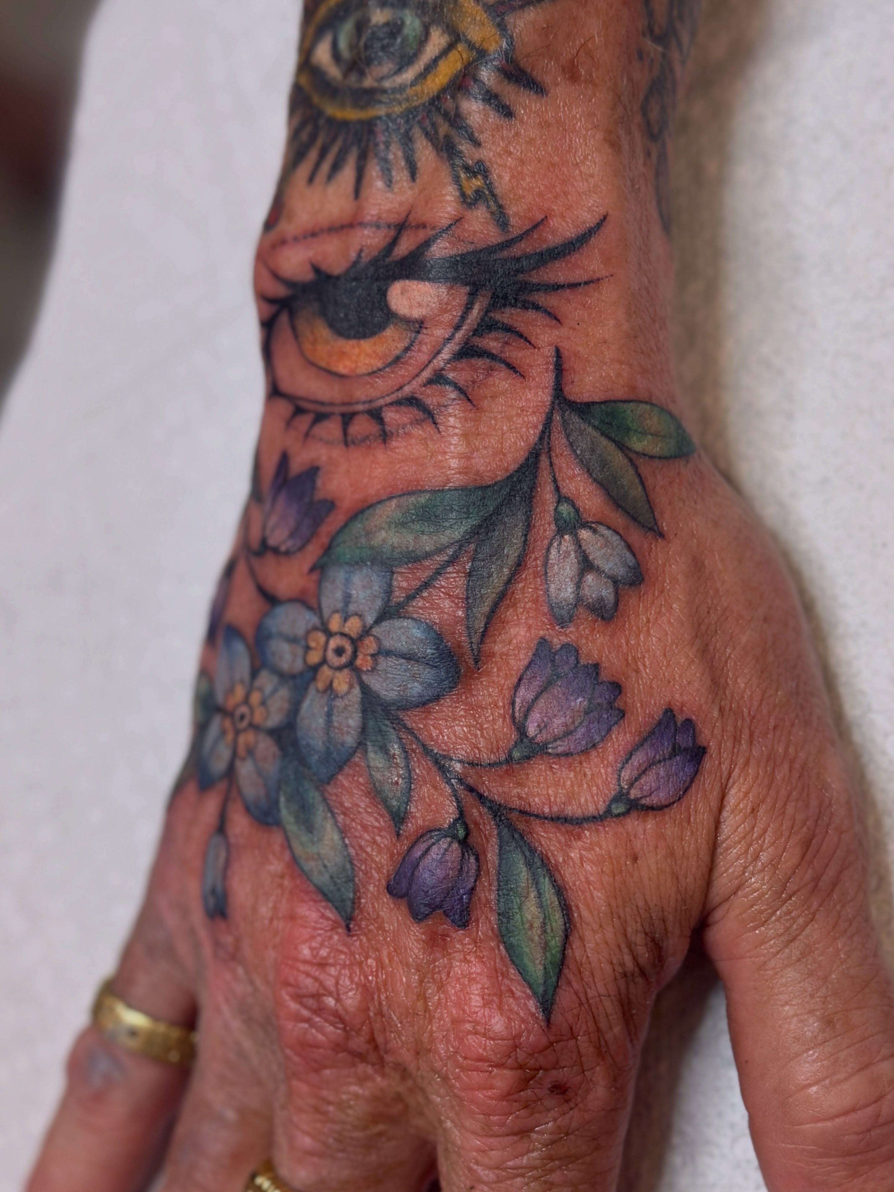 Eye and floral bouquet American traditional tattoo on the hand by Dani Di Pietrantonio