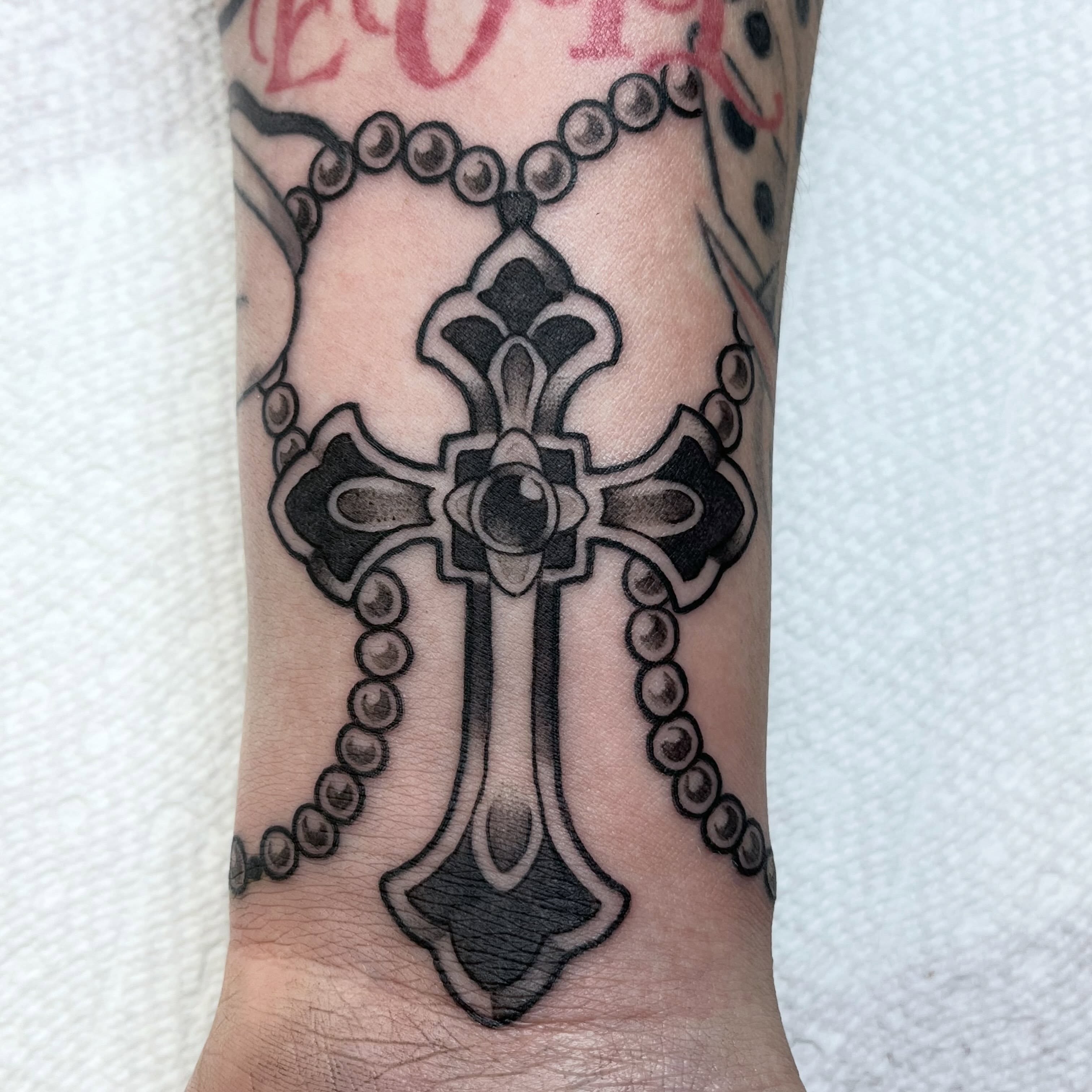 Cross and rosary black and grey tattoo on the forearm by ᴴᴬᴺᴺᴬᴴ ᴿᵁᴰᴰᴱᴸᴸ