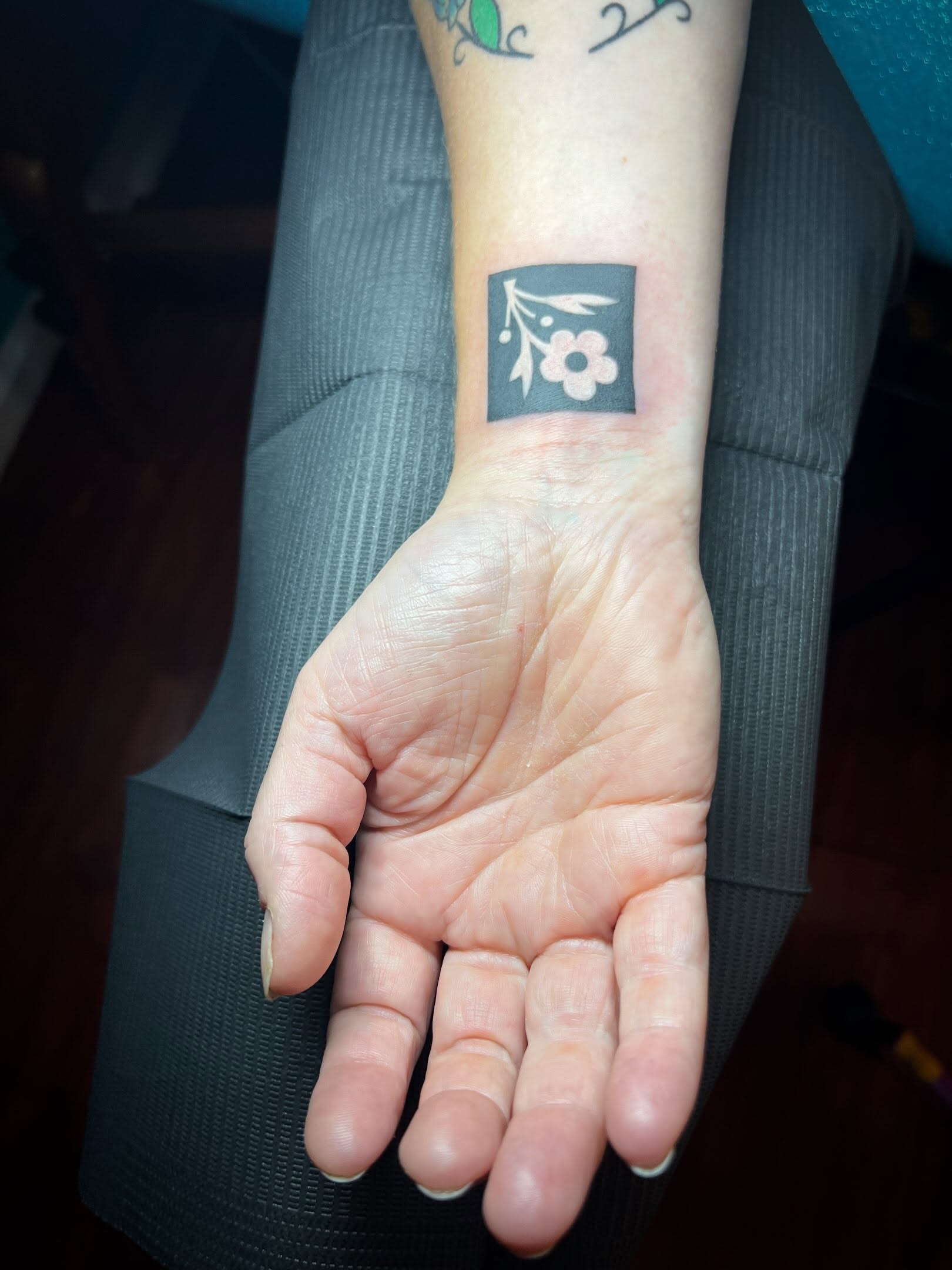 Flower and branch black and grey tattoo on the forearm by Tattoo Kayla
