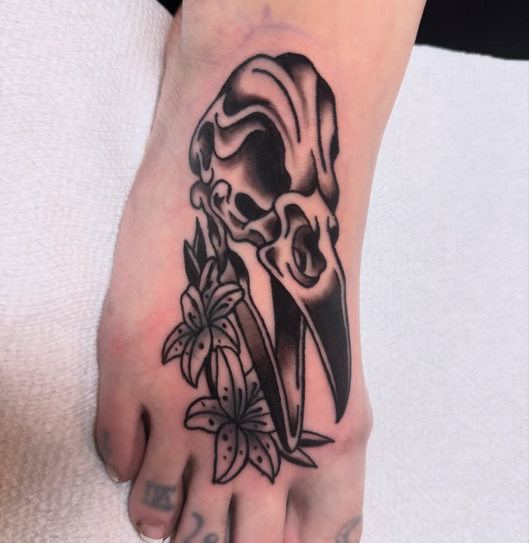 Lily and skull black and grey tattoo on the foot by Shelby