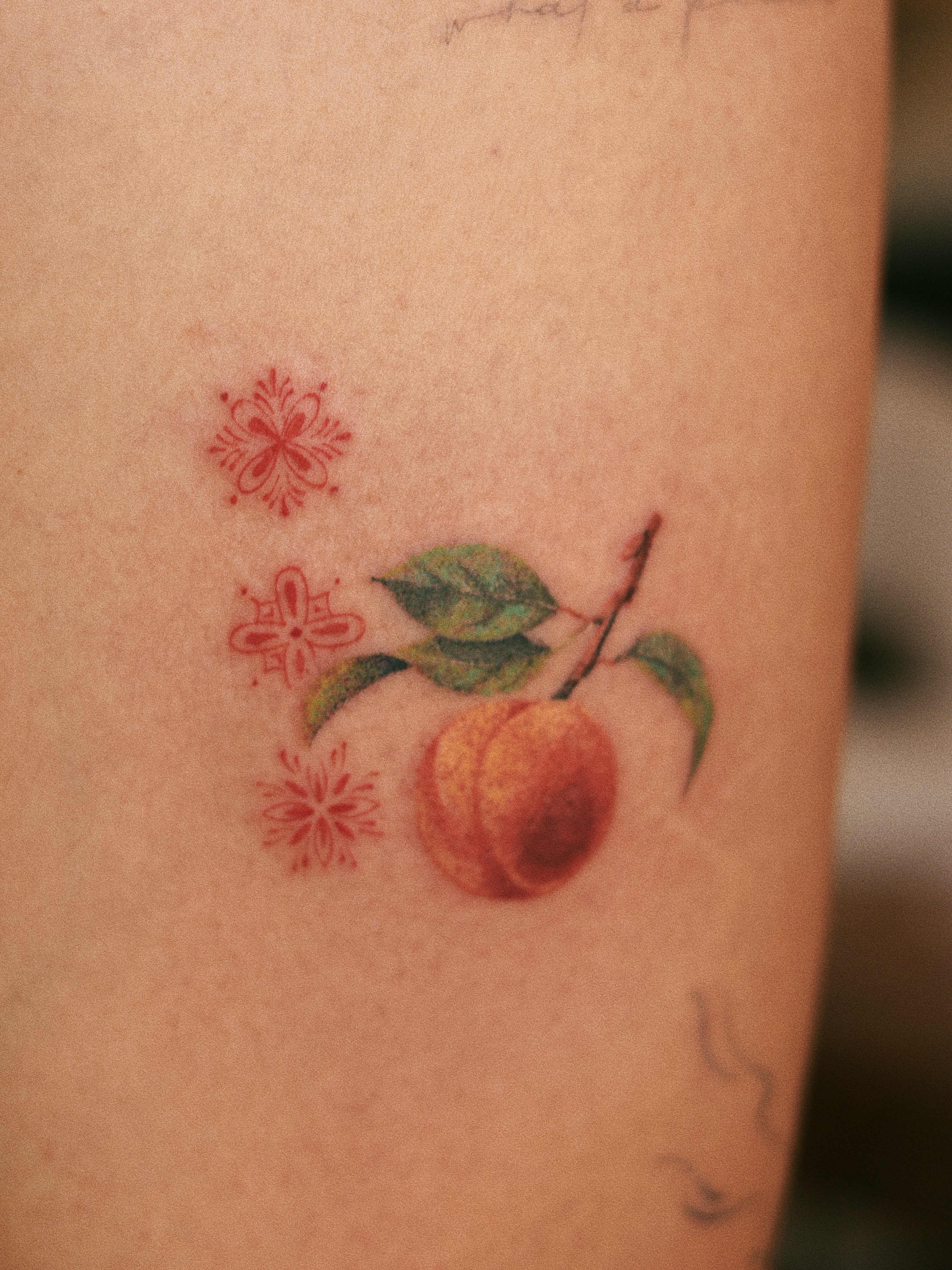 Peach and flowers realism tattoo on the forearm by Micah Light (color micro realism, Los Angeles, California