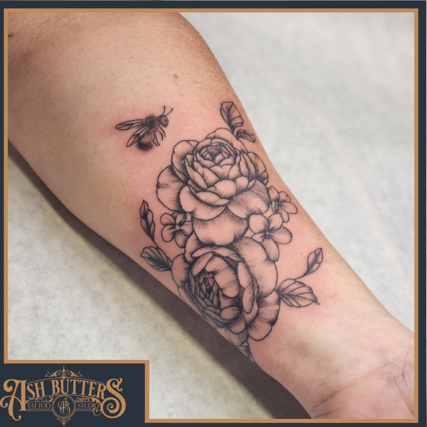 Roses and bee realism tattoo on the forearm by Ash Butters
