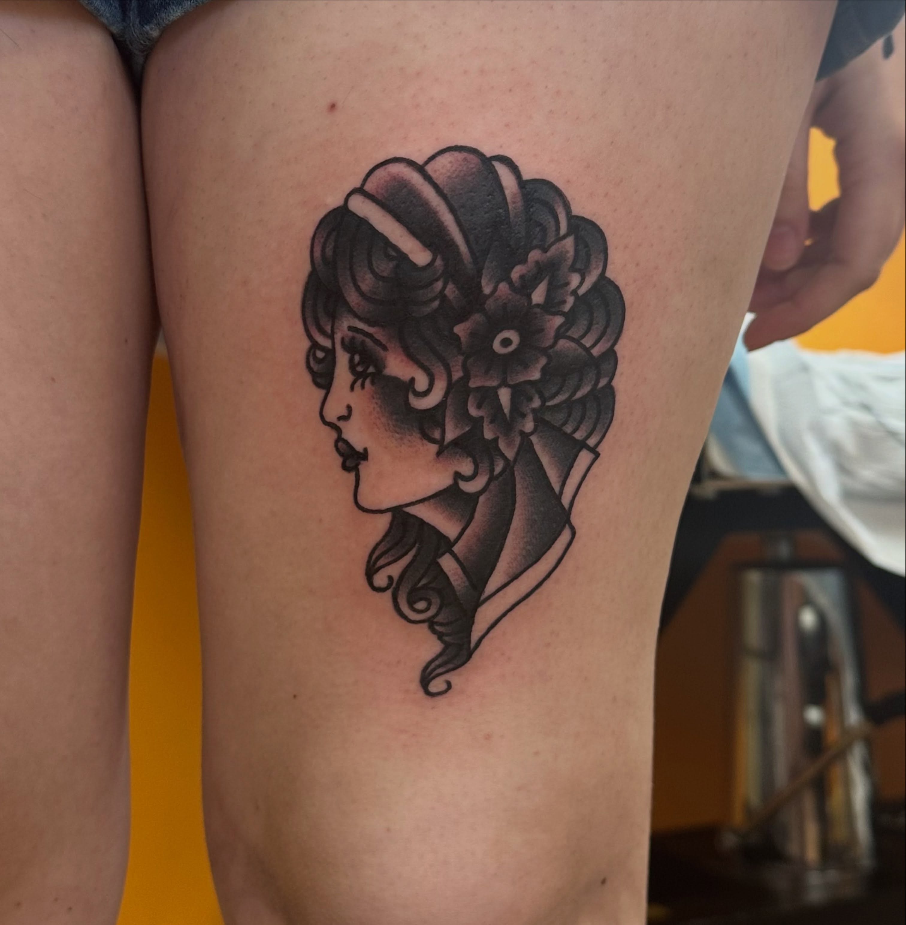 Woman with floral crown American traditional tattoo on the thigh by norawillstattoo