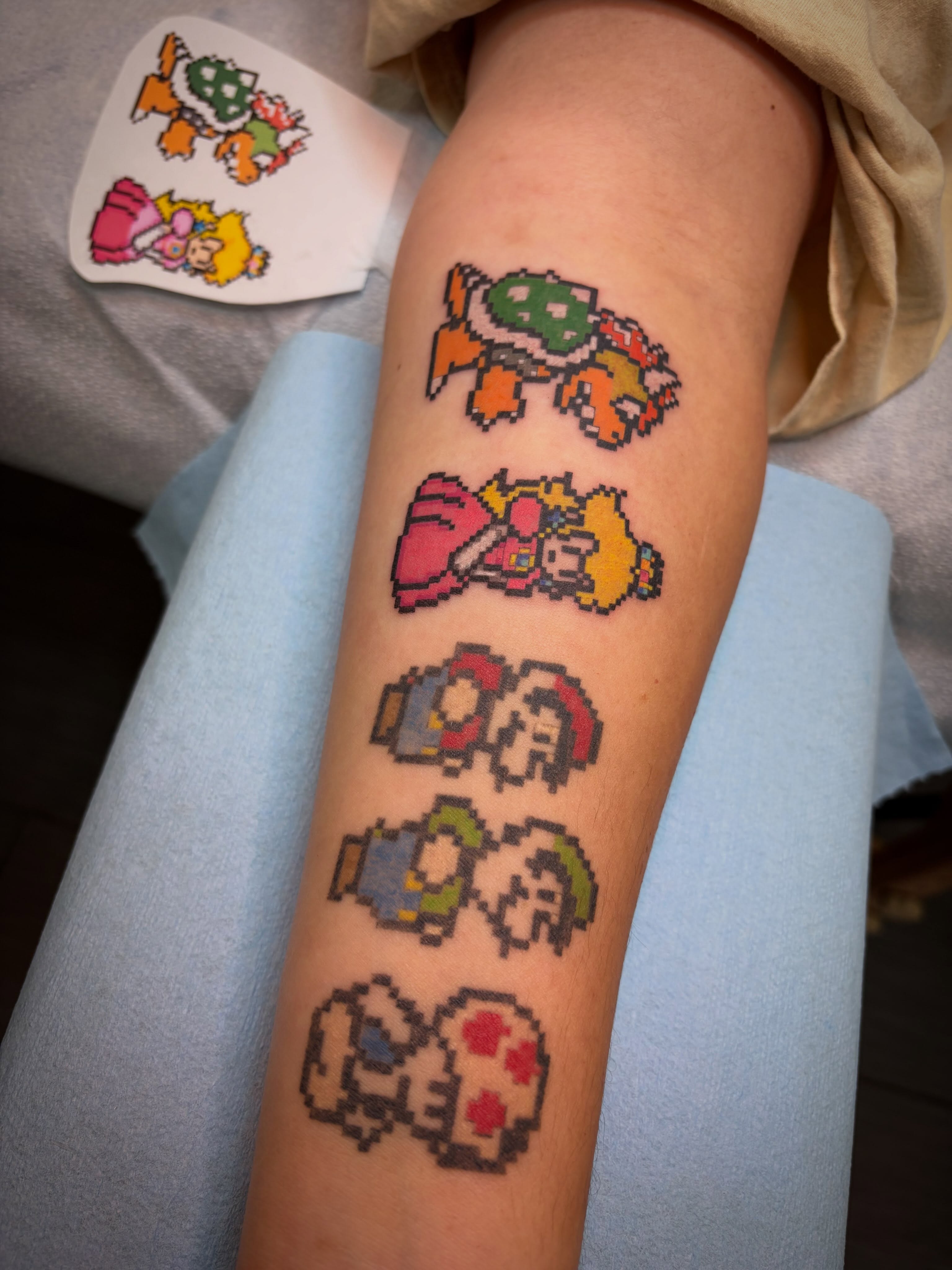 Pixel art characters dotwork tattoo on the forearm by Peach ๐, Portland, Oregon