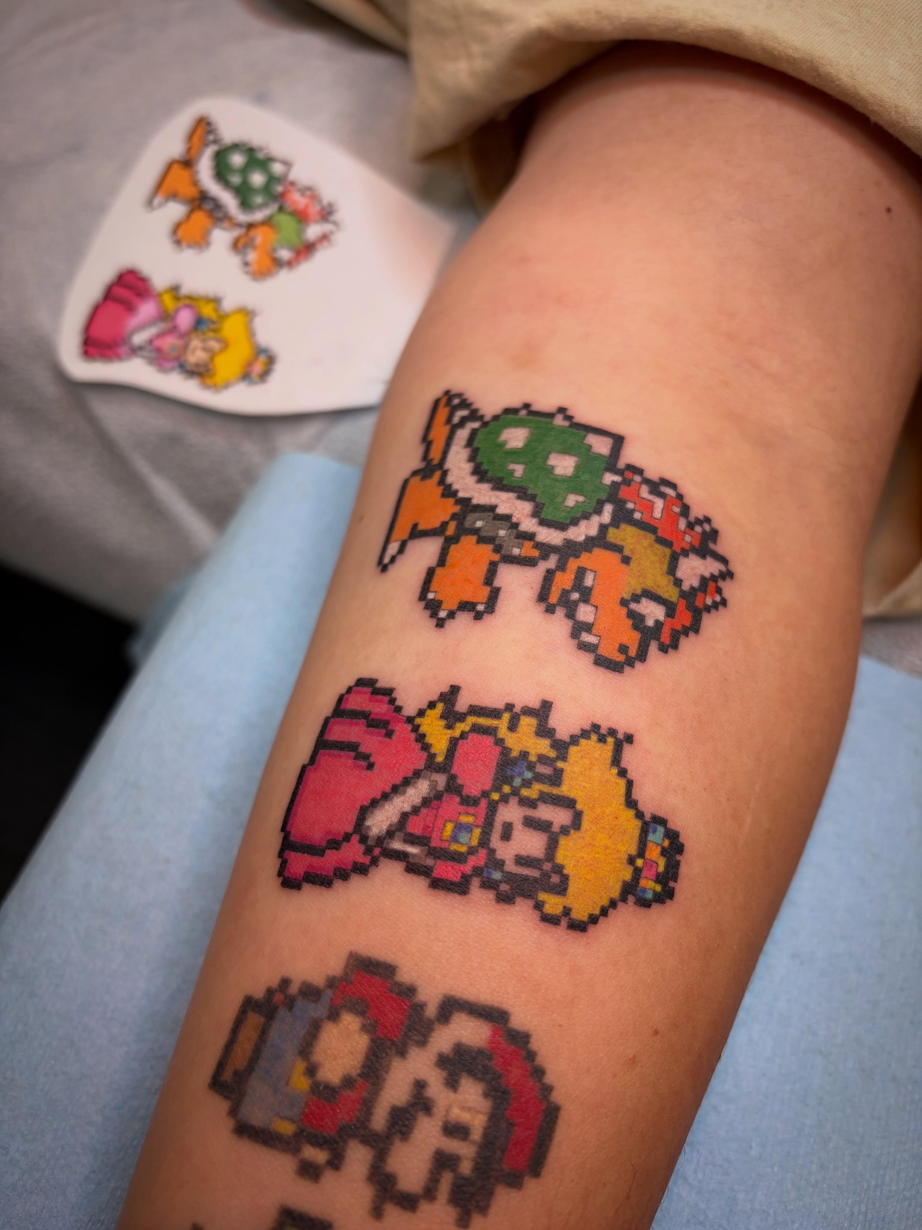 Pixel art characters dotwork tattoo on the forearm by Peach ๐, Portland, Oregon