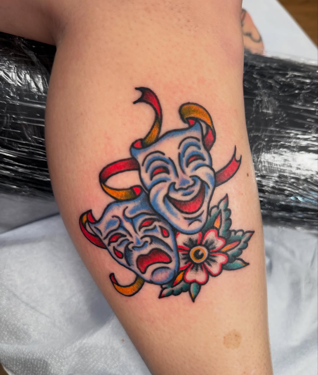Theater masks American traditional tattoo on the thigh by Jesse Boss, Nashville, Tennessee