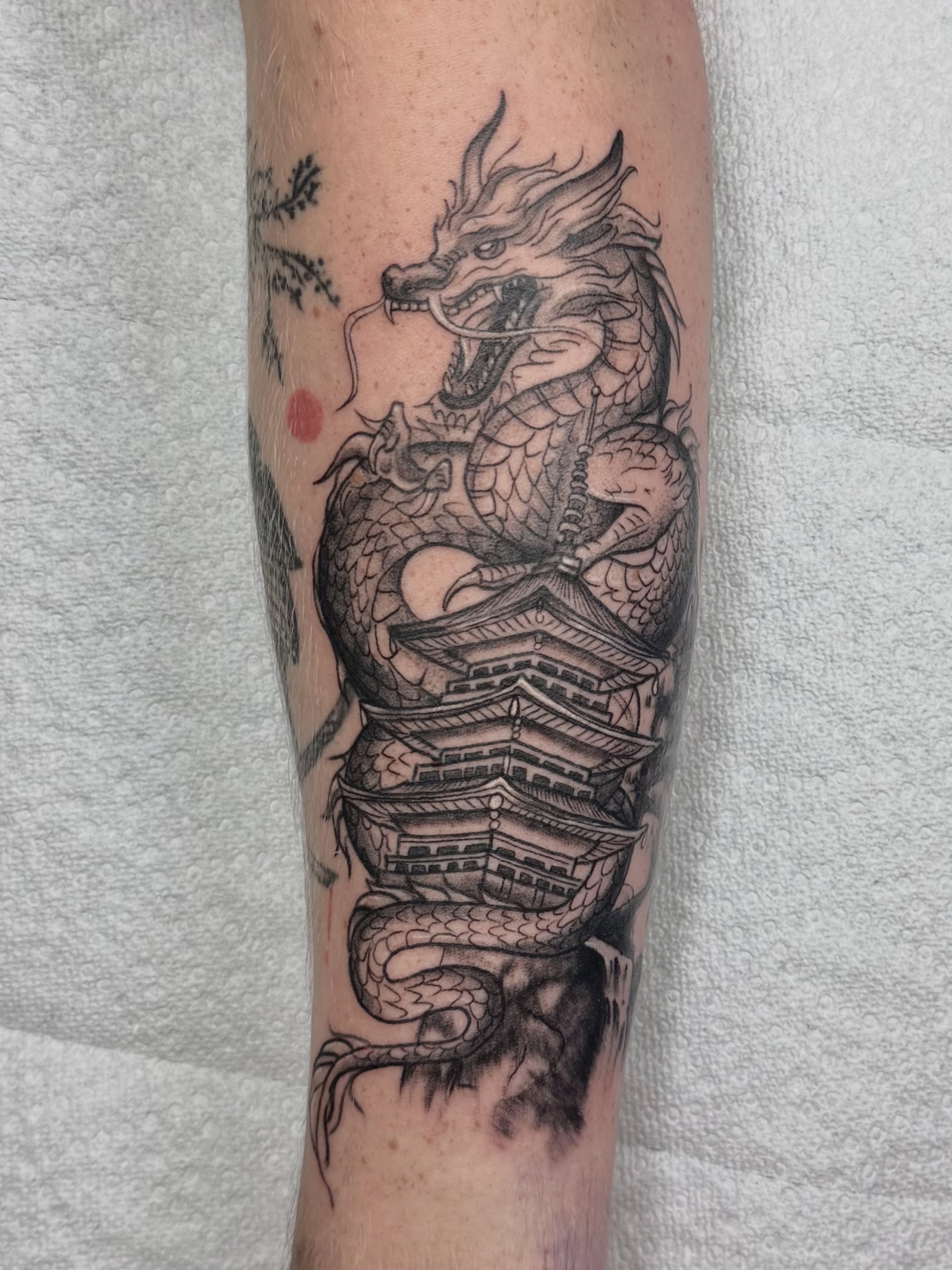 Dragon and pagoda realism tattoo on the forearm by Skylar Sheeley