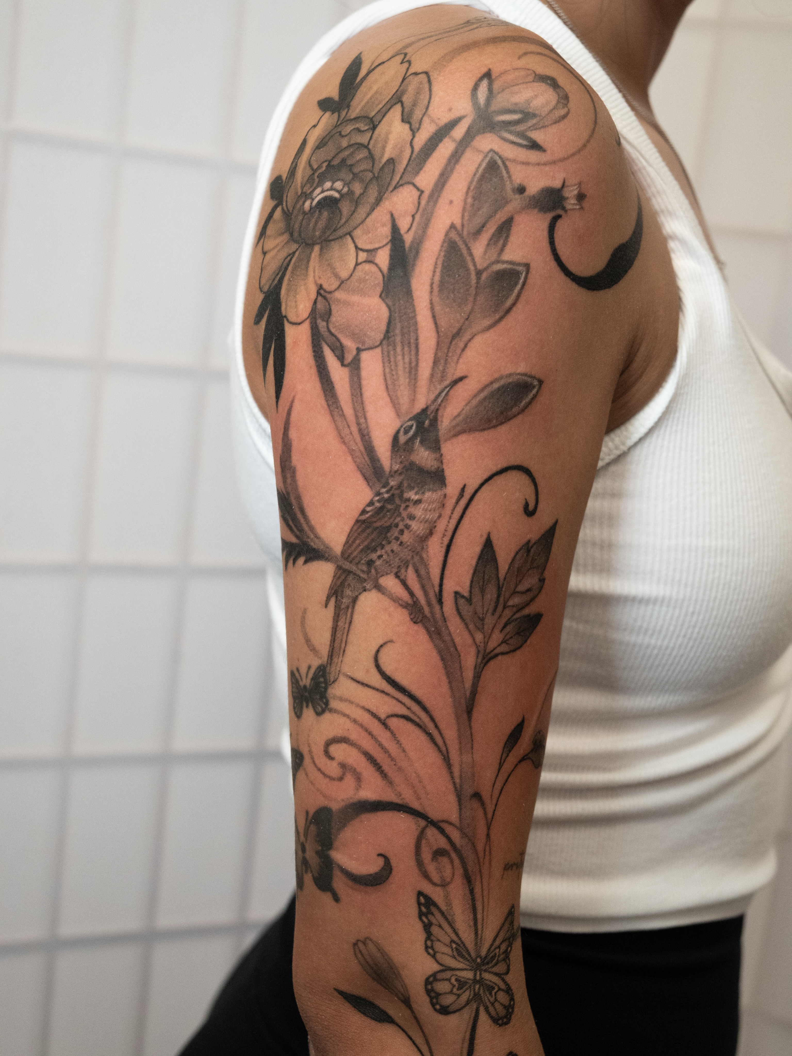 Bird and floral realism tattoo on the forearm by Neri Gersaint