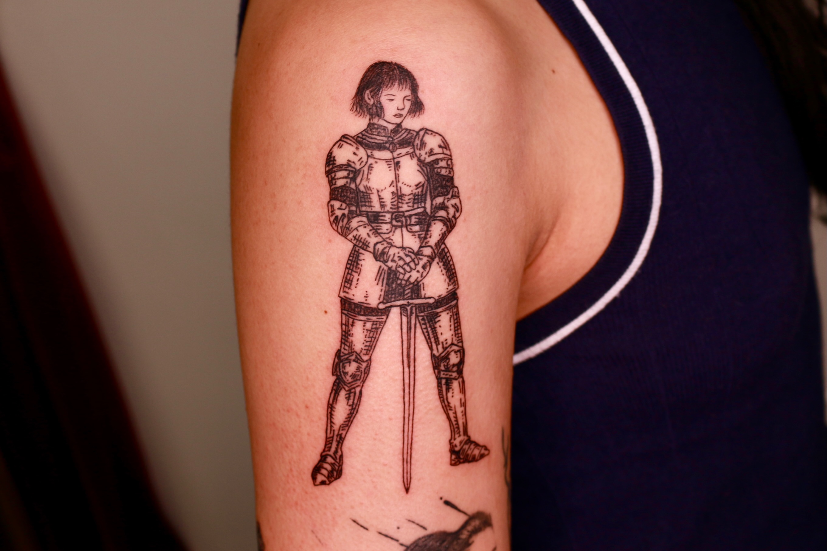 Woman in armor black and grey tattoo on the upper arm by Mike