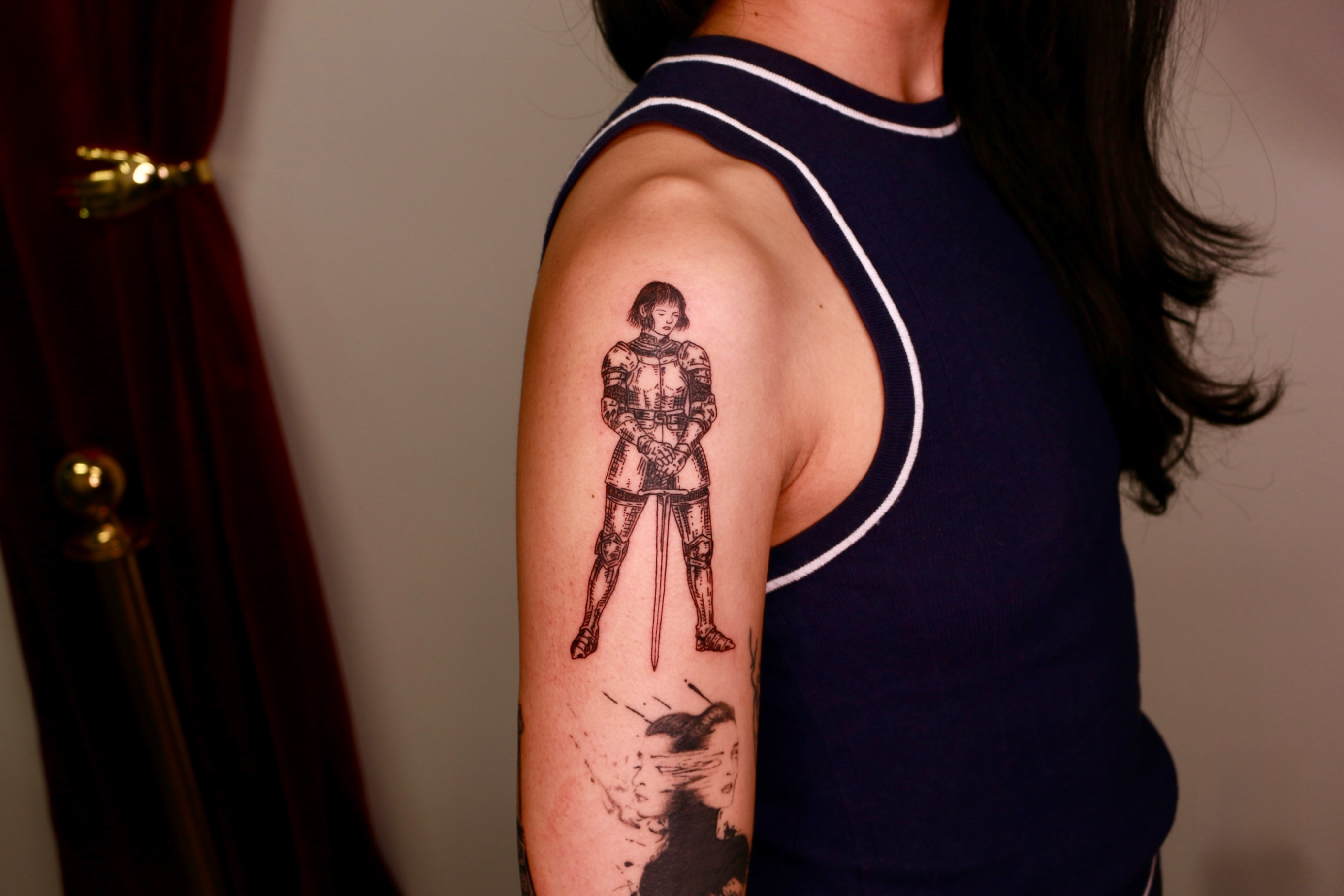 Knight in armor black and grey tattoo on the upper arm by Mike
