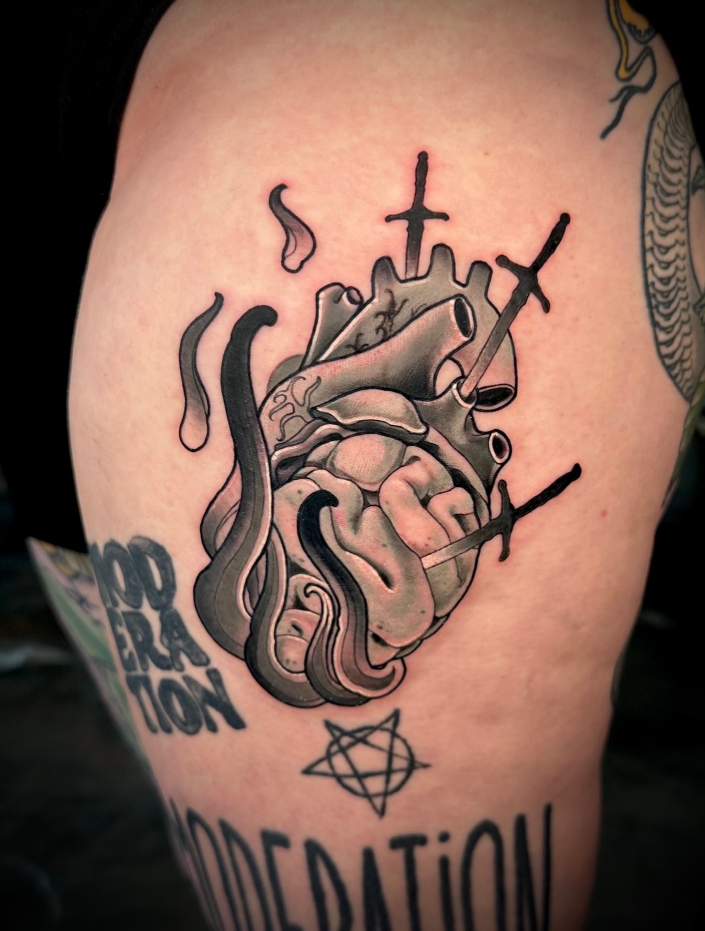 Heart with cross black and grey tattoo on the thigh by Teddi Garson