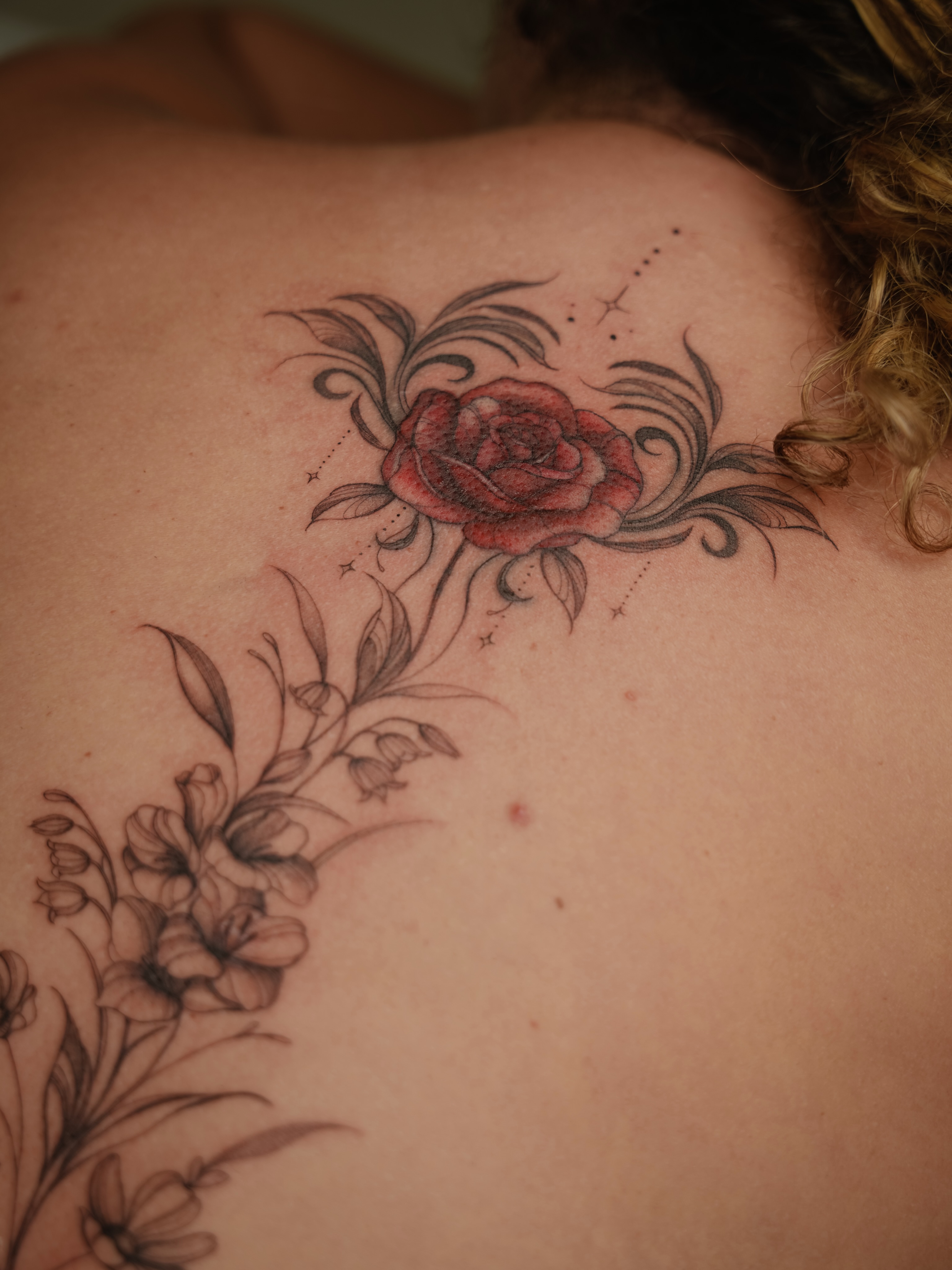 Red rose black and grey tattoo on the back by Laura Gomez Tattoos