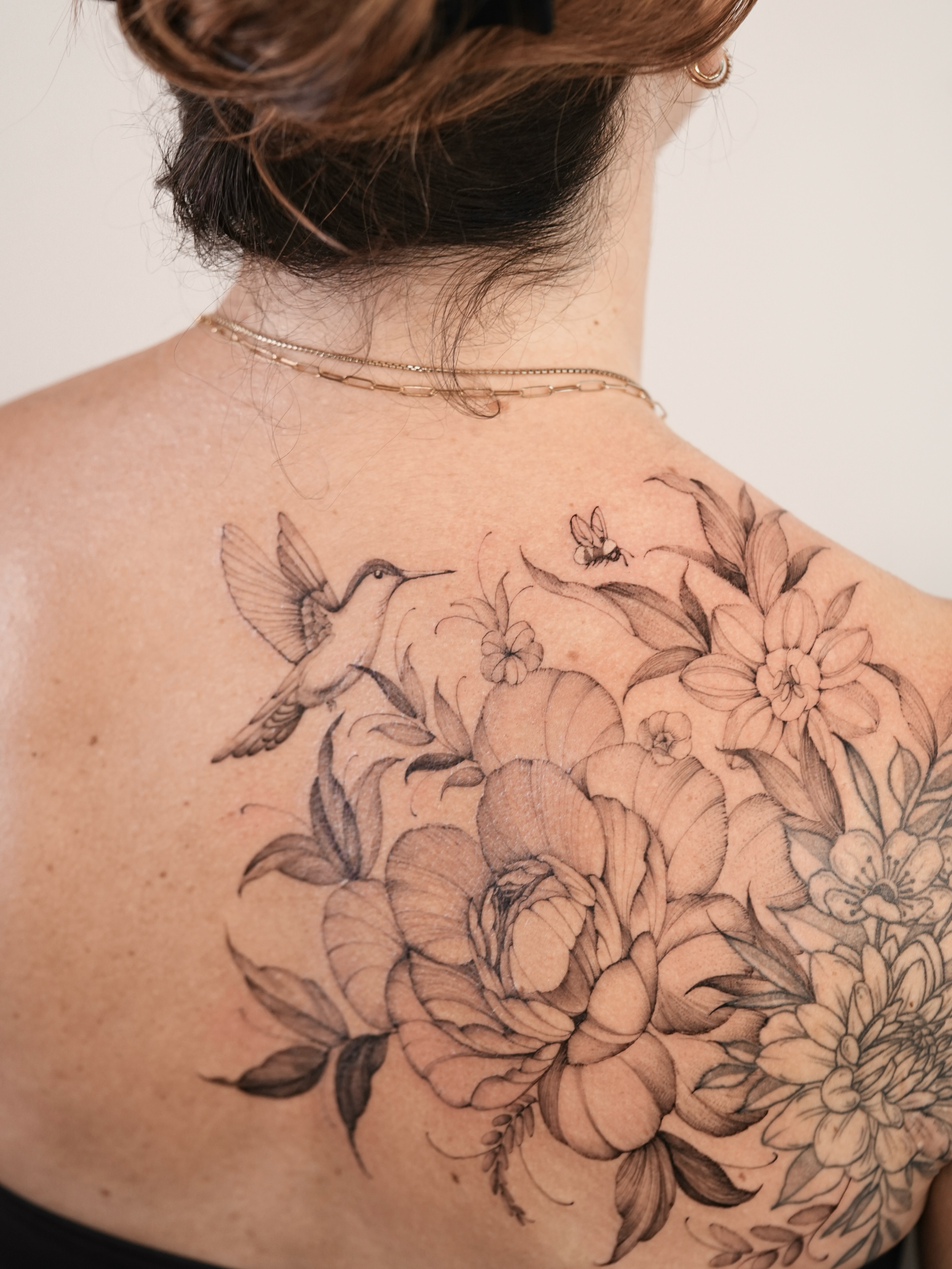 Floral and hummingbird black and grey tattoo on the back by Zalina Loriia