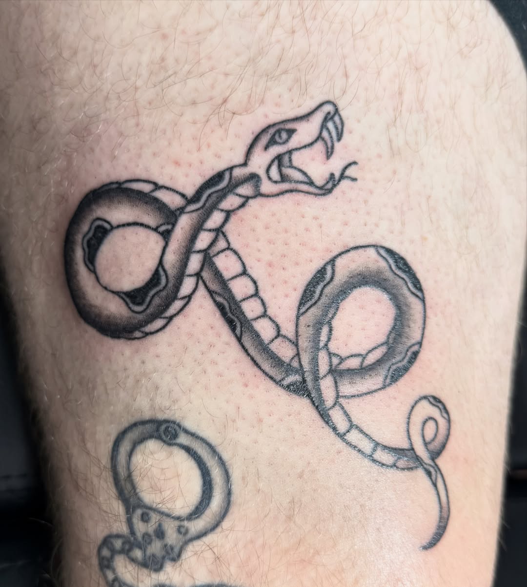 Snake black and grey tattoo on the thigh by Hunter Beyer