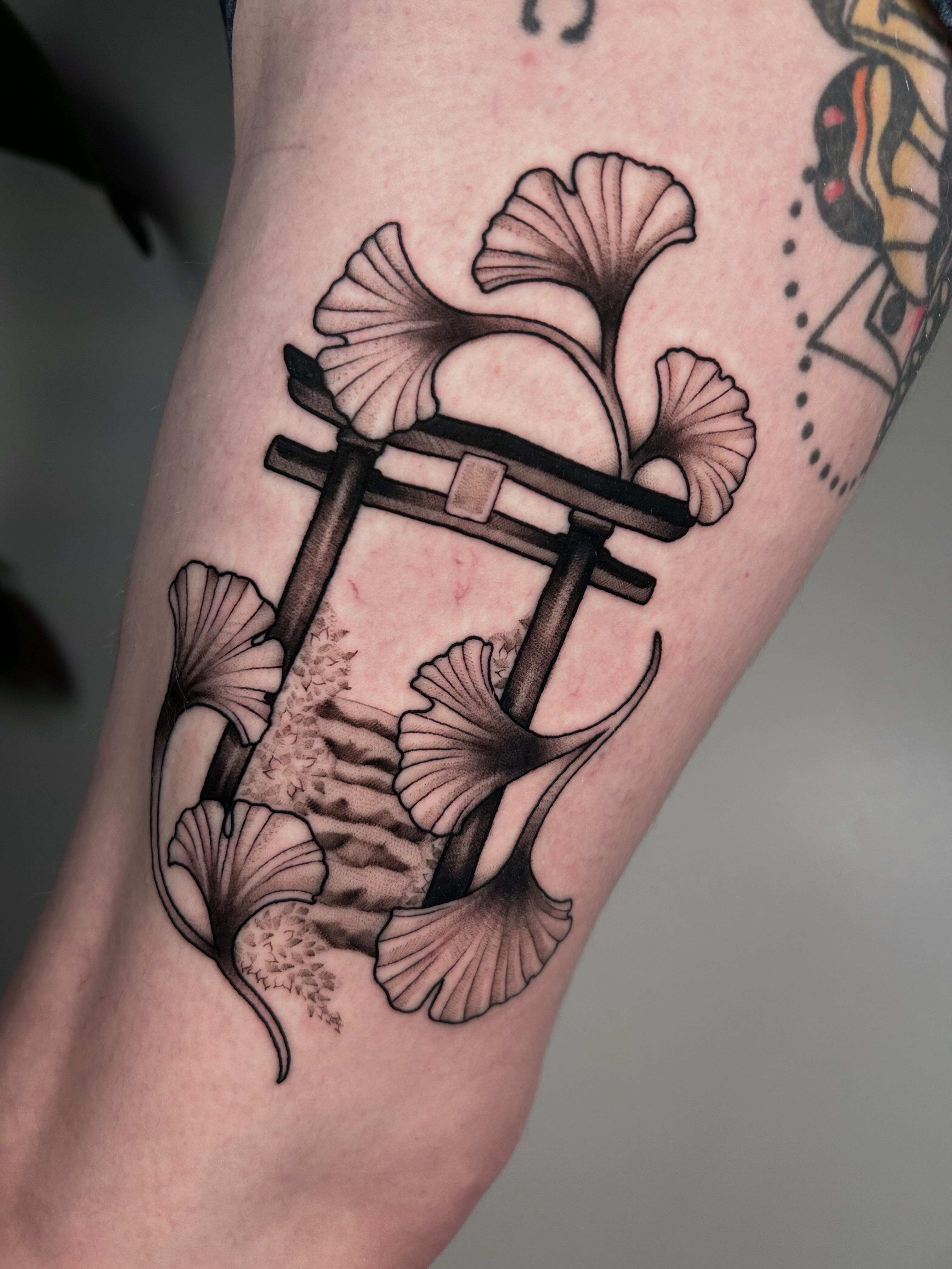 Torii gate and ginkgo leaves black and grey tattoo on the forearm by Salt Lake City tattoo artist