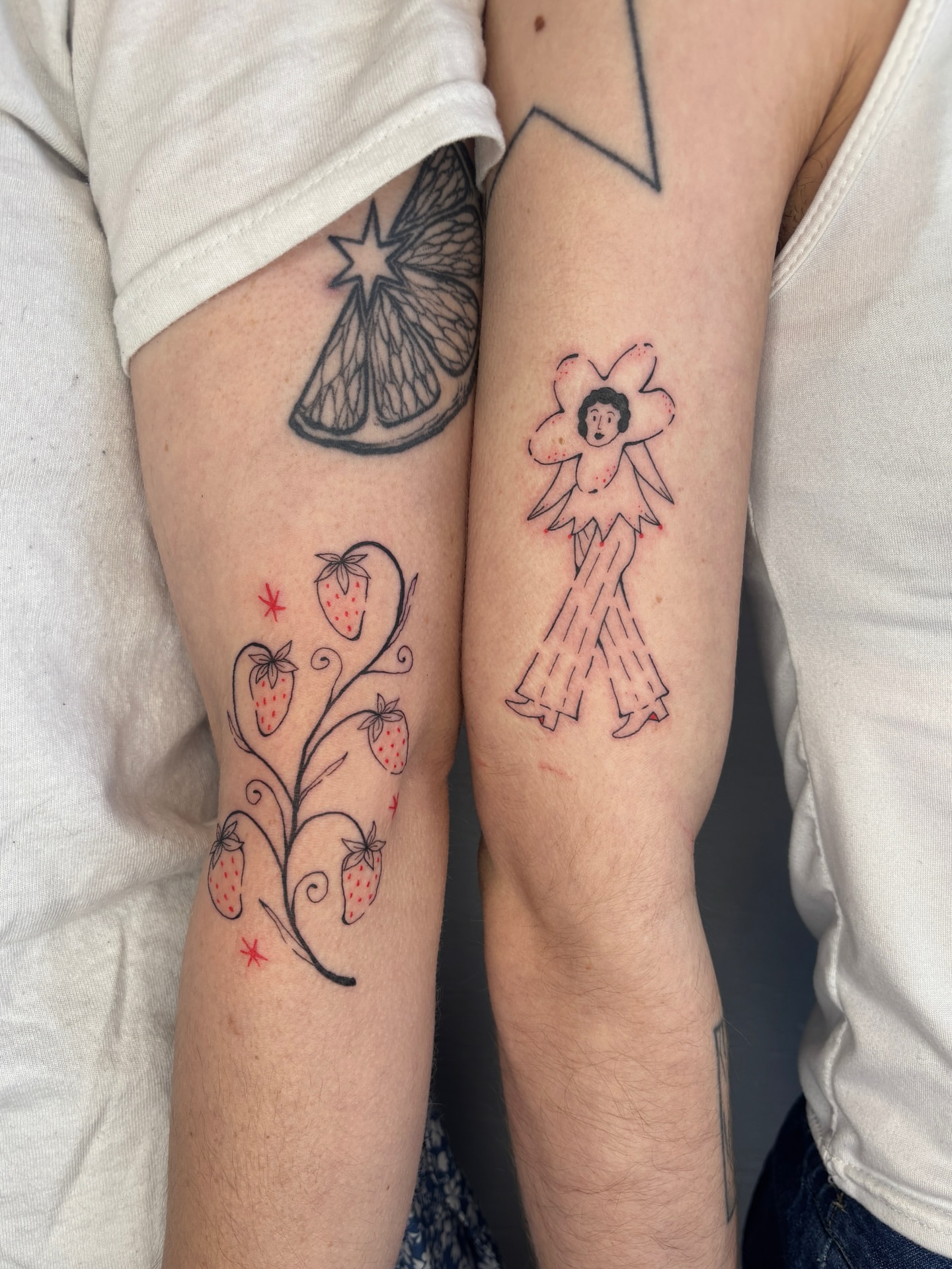 Strawberries and angel illustrative tattoo on the forearm by Raye