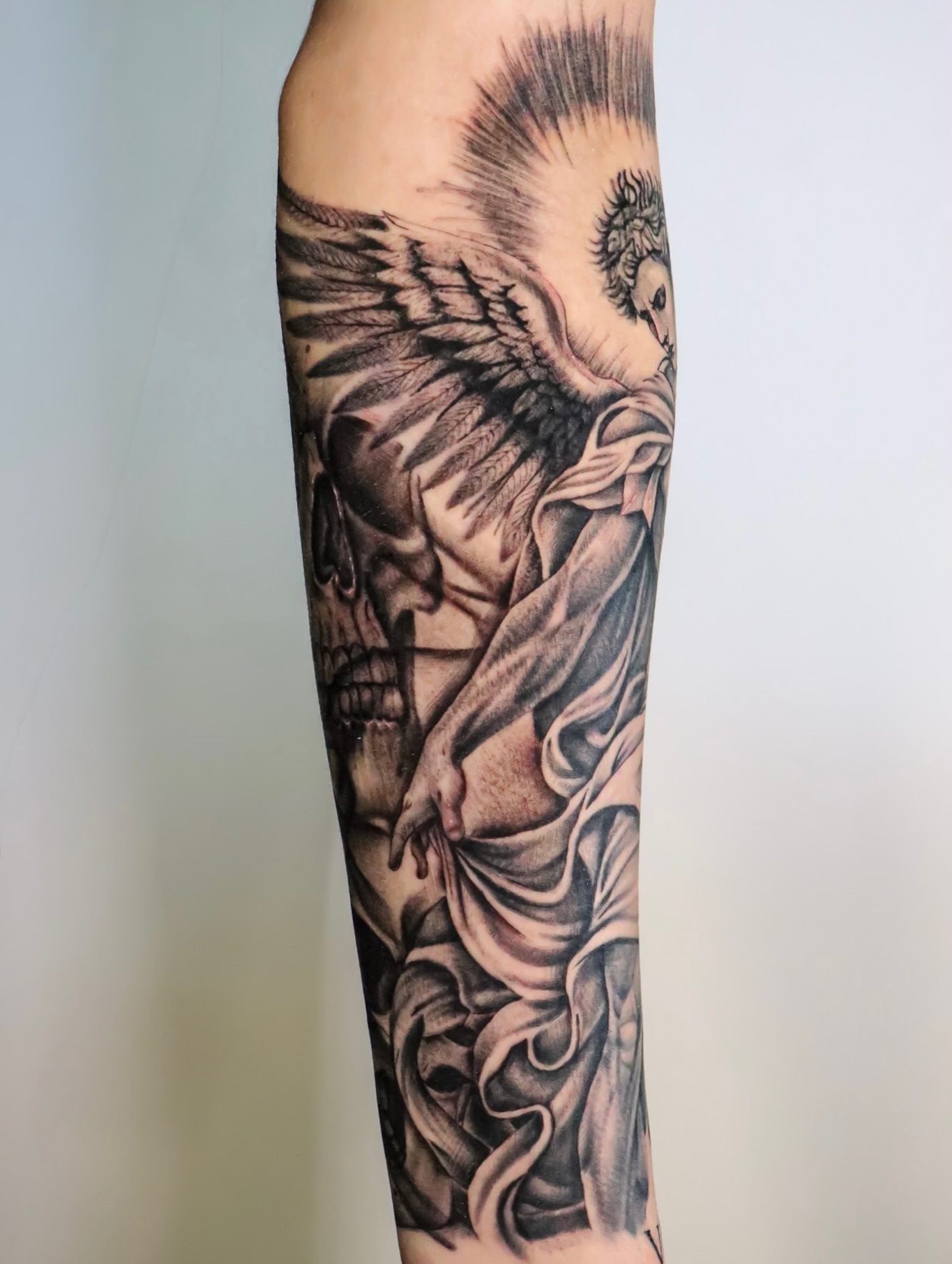 Angel and skull realism tattoo on the forearm by Angel Tattoos