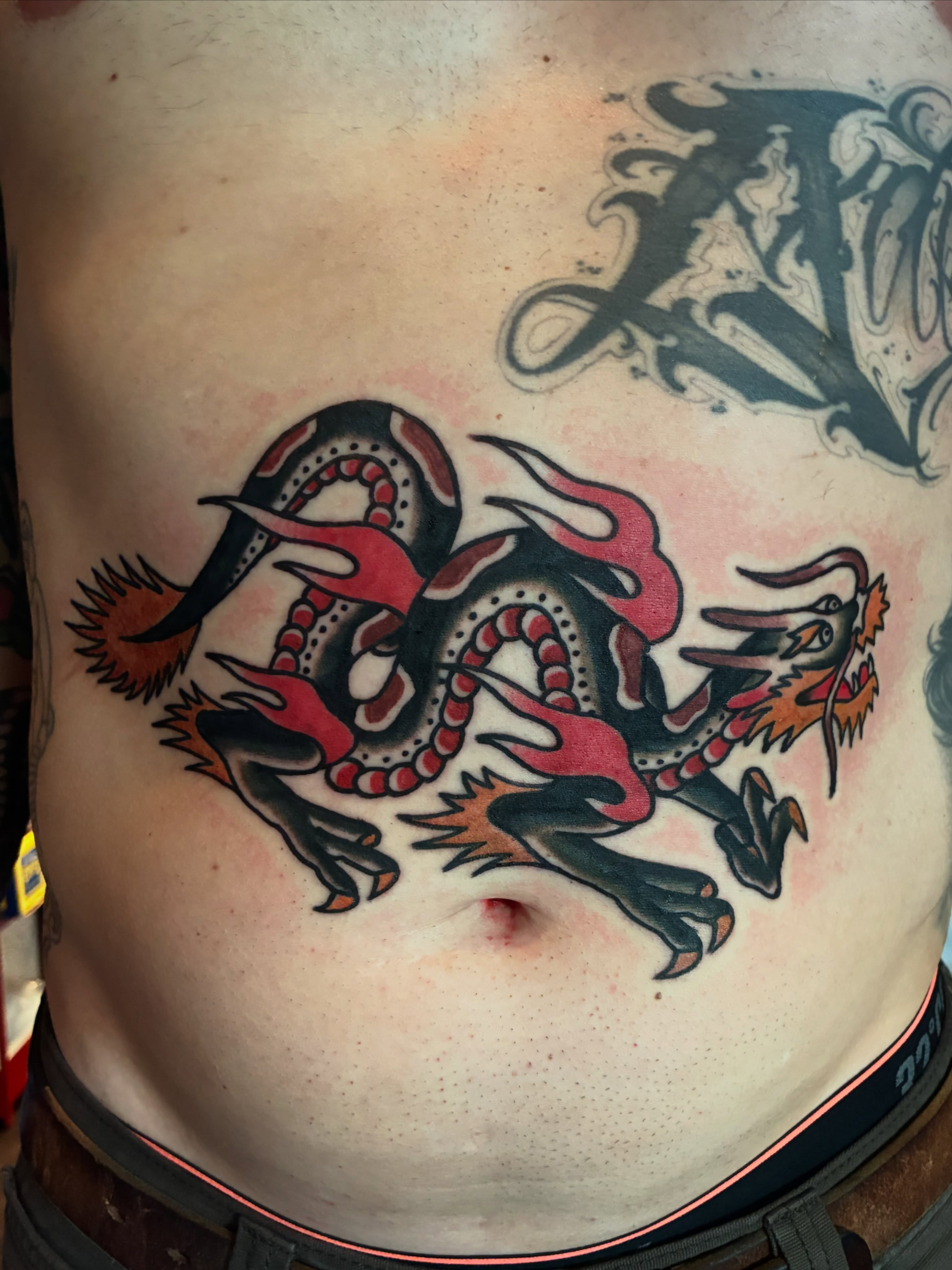Dragon American traditional tattoo on the torso by Mike Hudgins