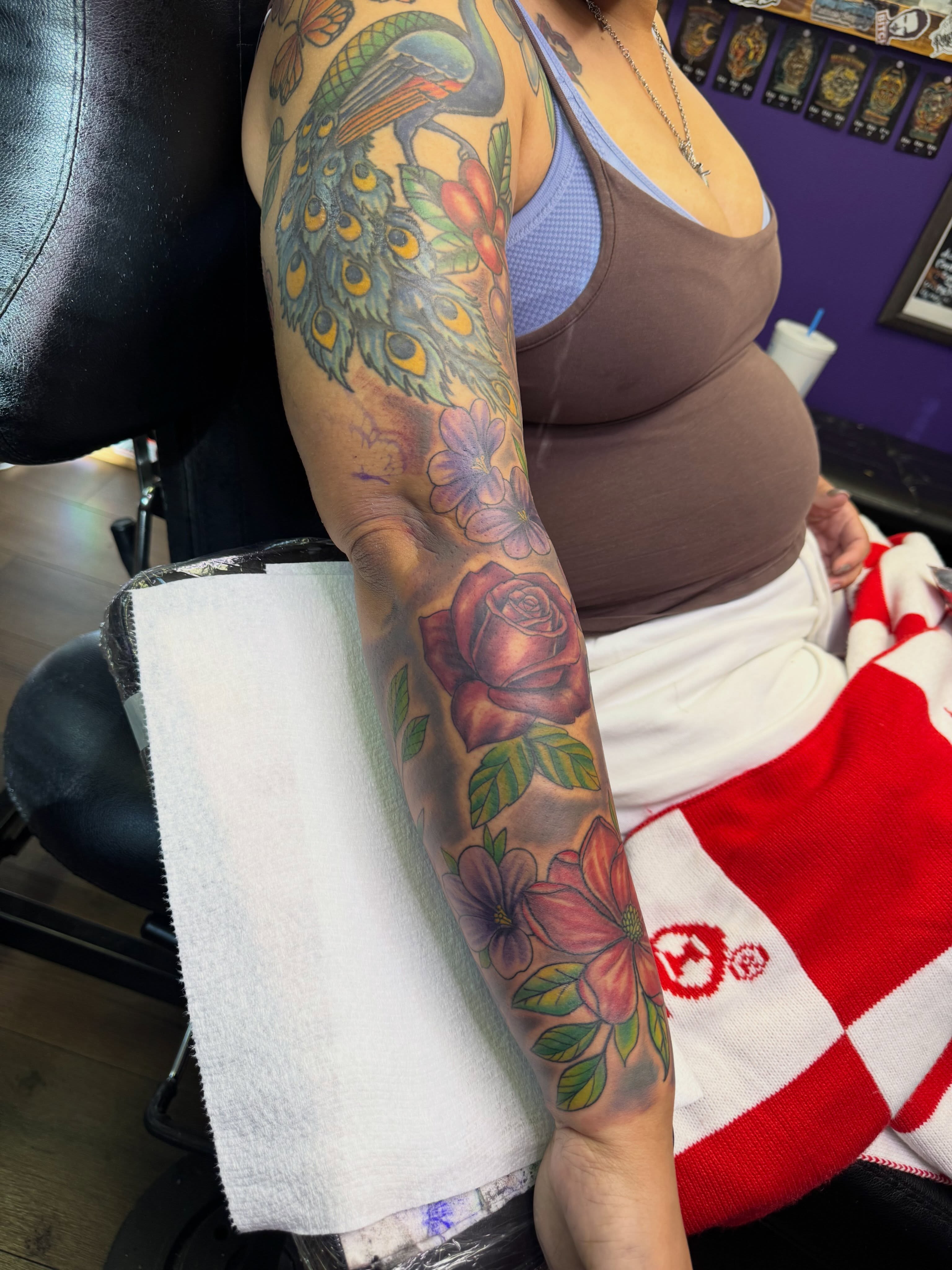 Peacock and flowers American traditional tattoo on the forearm by Christian Goines, Memphis, Tennessee