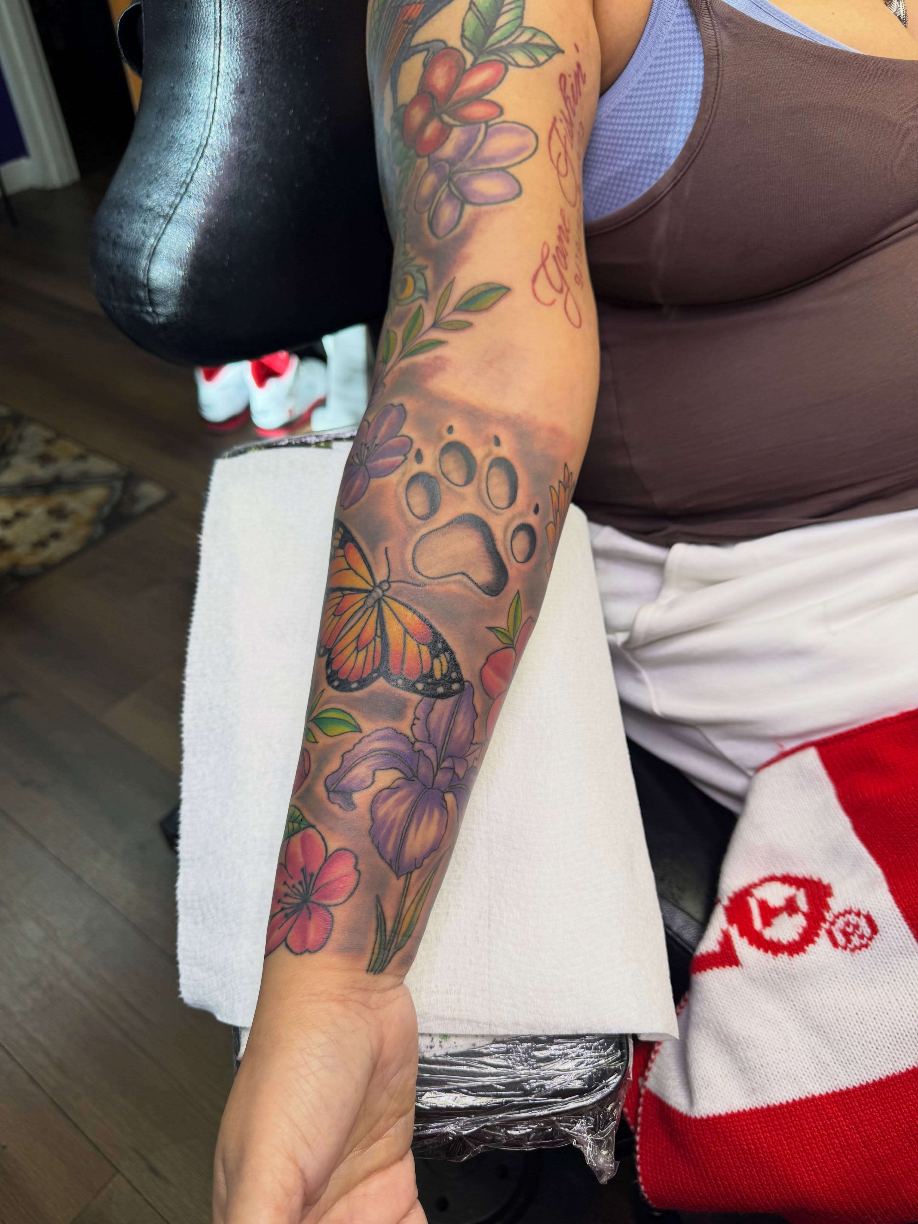 Floral and paw print new school tattoo on the forearm by Christian Goines, Memphis, Tennessee