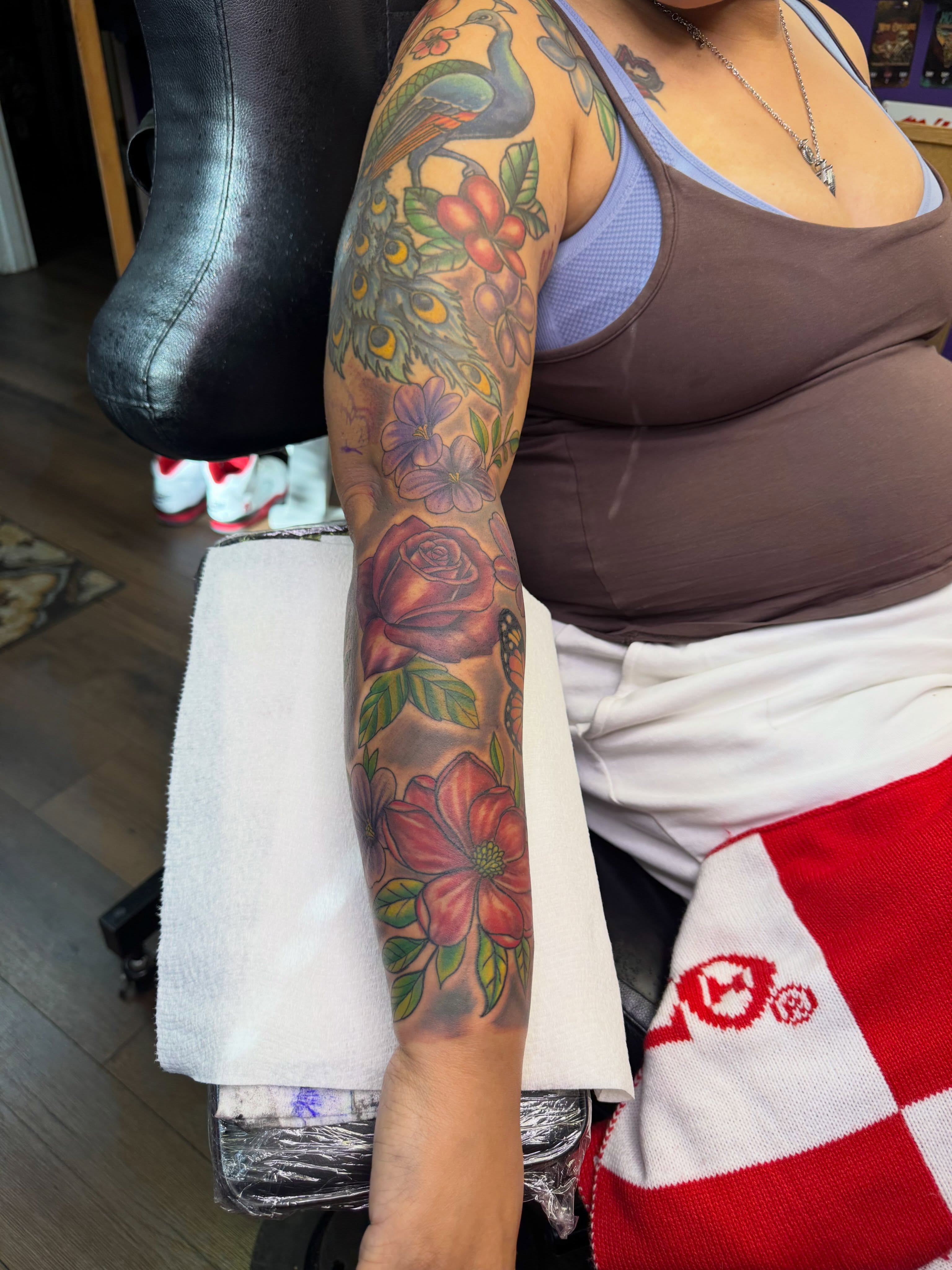 Peacock and floral American traditional tattoo on the upper arm by Christian Goines, Memphis, Tennessee