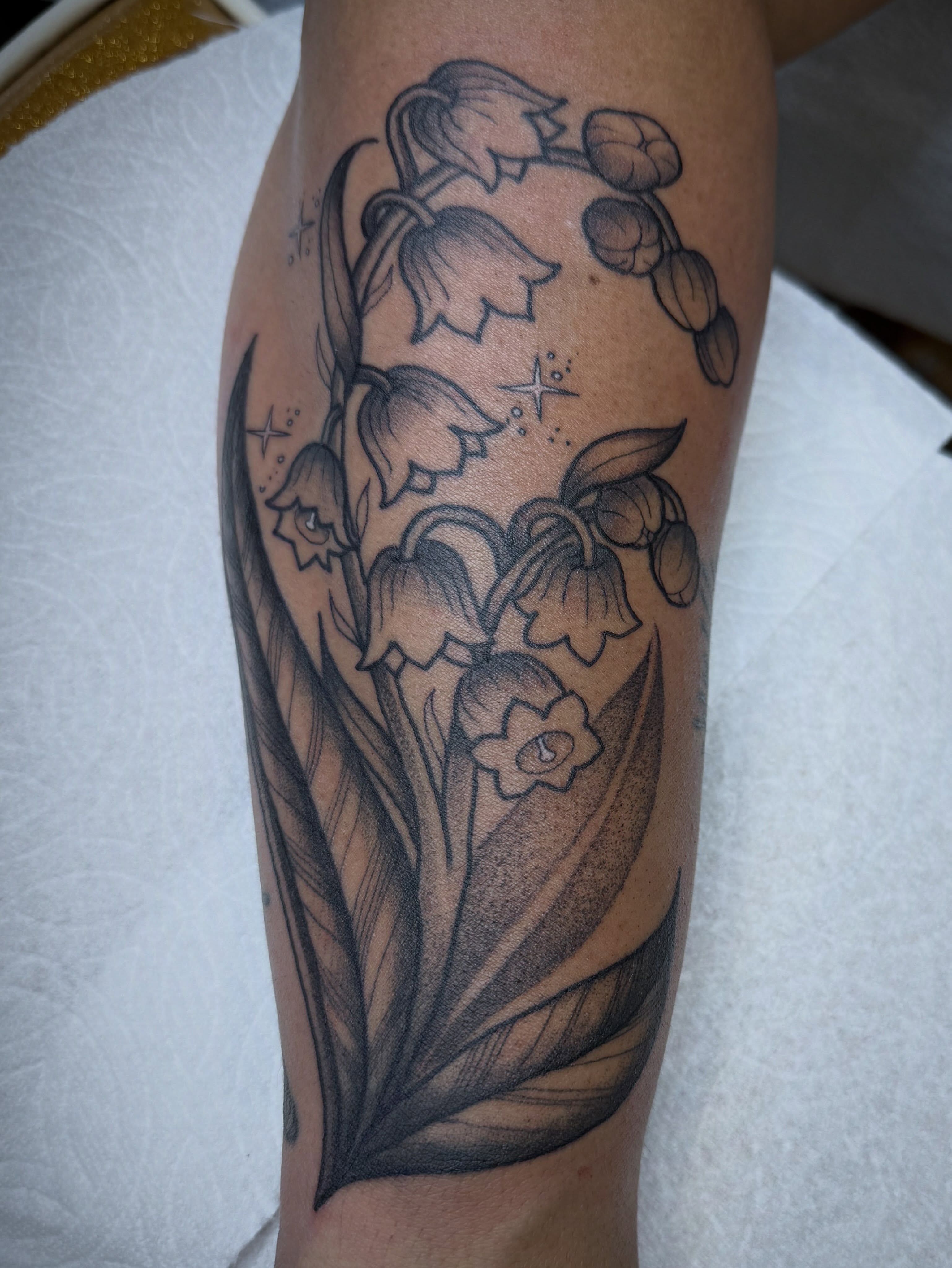 Lily of the valley black and grey tattoo on the forearm by Tanya Gomez