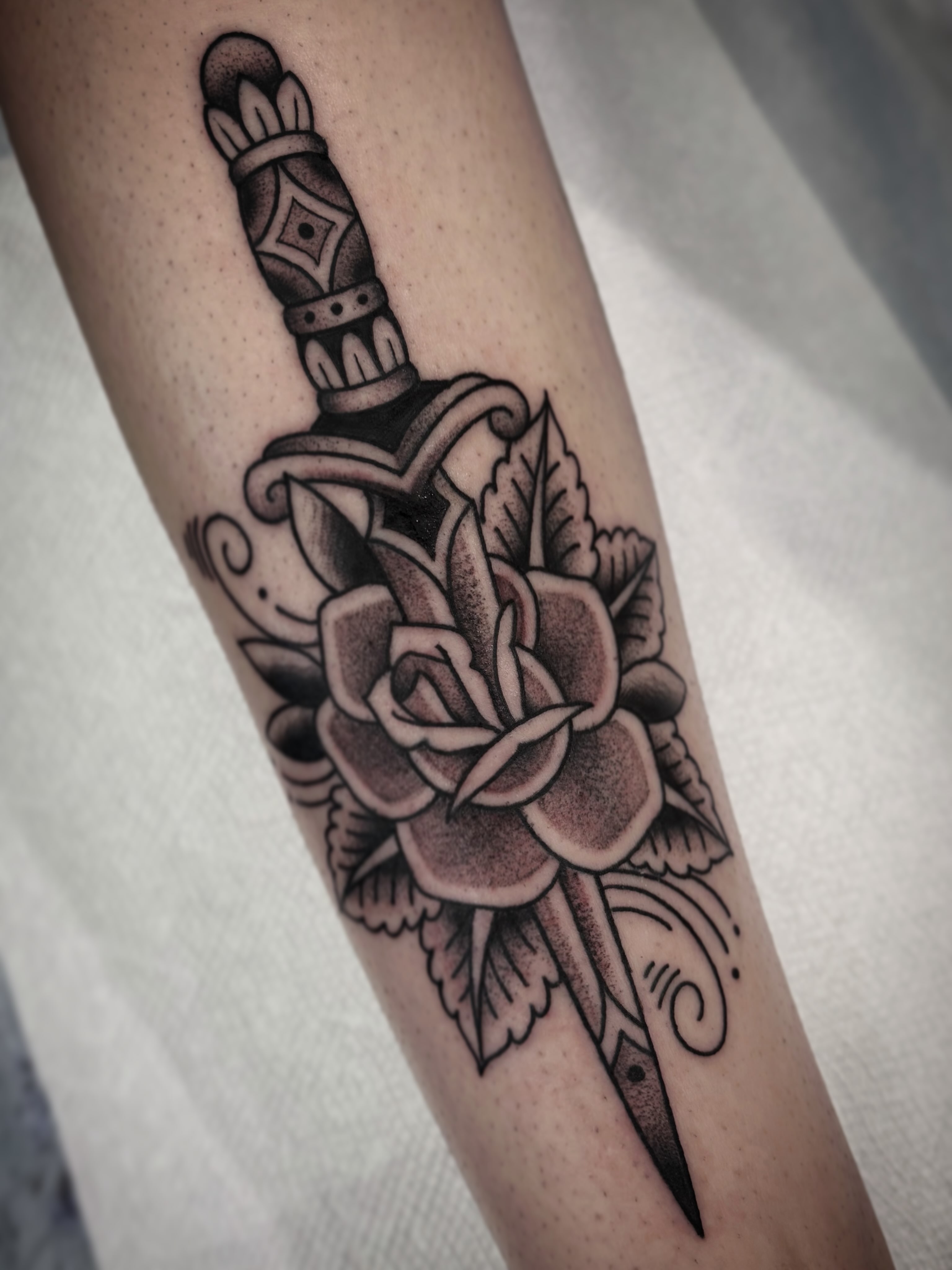 Knife and rose American traditional tattoo on the forearm by Kayla Shoffner