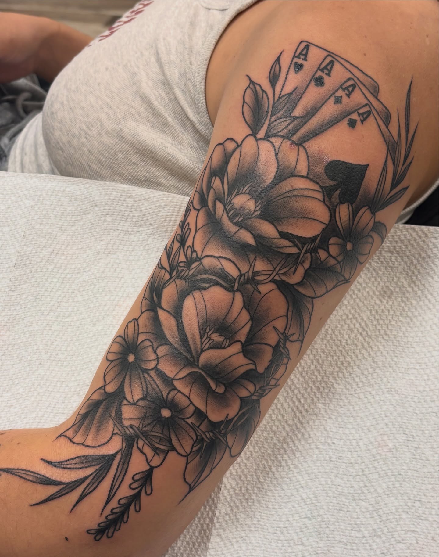 Flowers and playing cards black and grey tattoo on the forearm by Megan