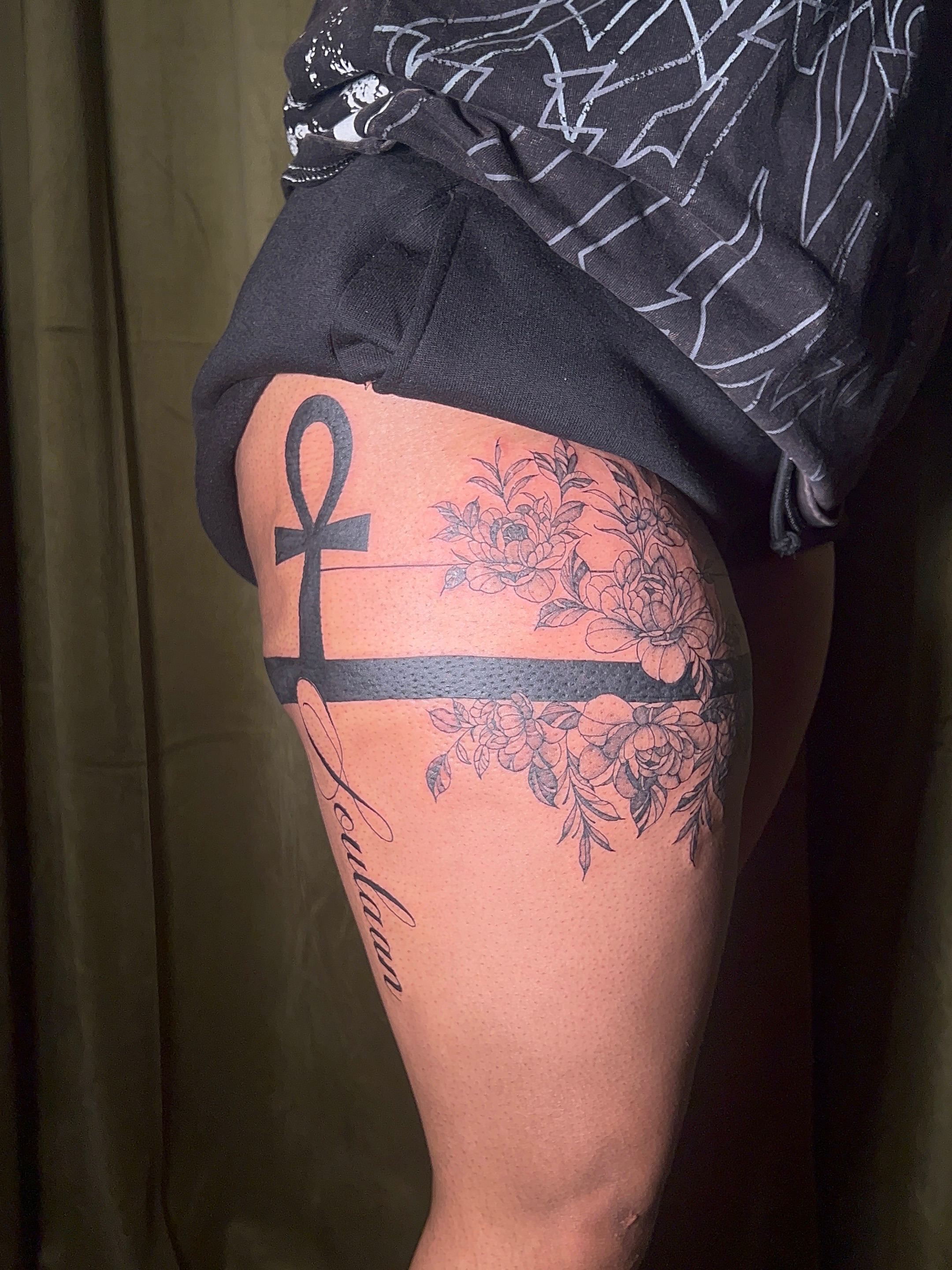 Floral arrangement with ankh black and grey tattoo on the thigh by V