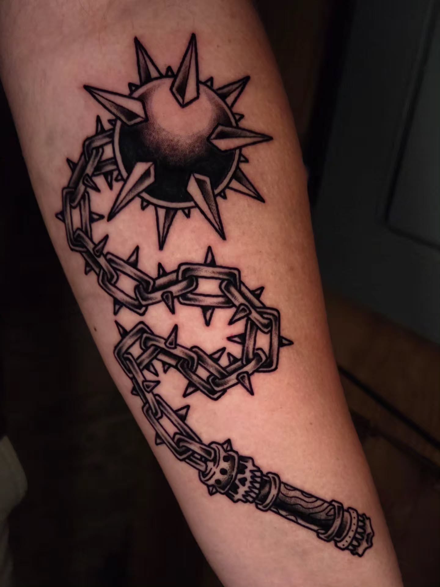 Spiked sun and chain black and grey tattoo on the forearm by Ian Kiser