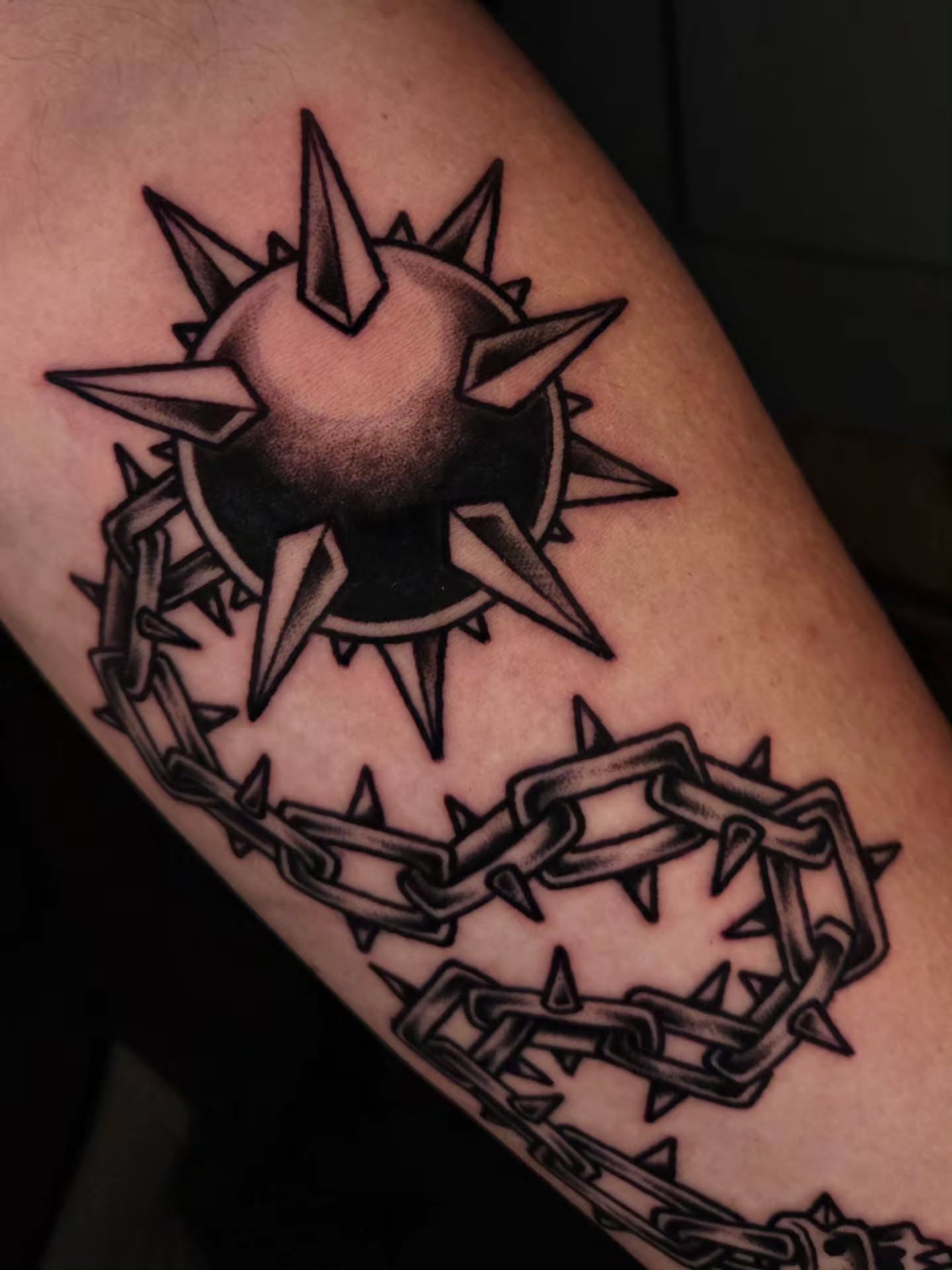 Spiked sun with barbed chain geometric tattoo on the forearm by Ian Kiser