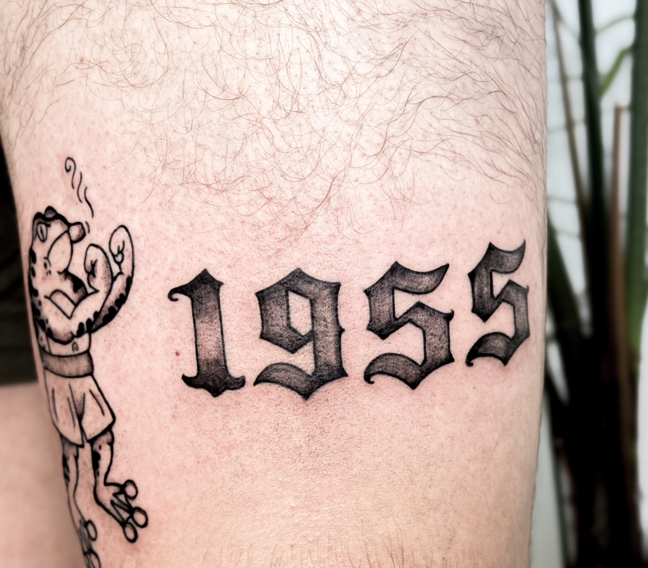 1955 black and grey tattoo on the thigh by Tatuajes Denver