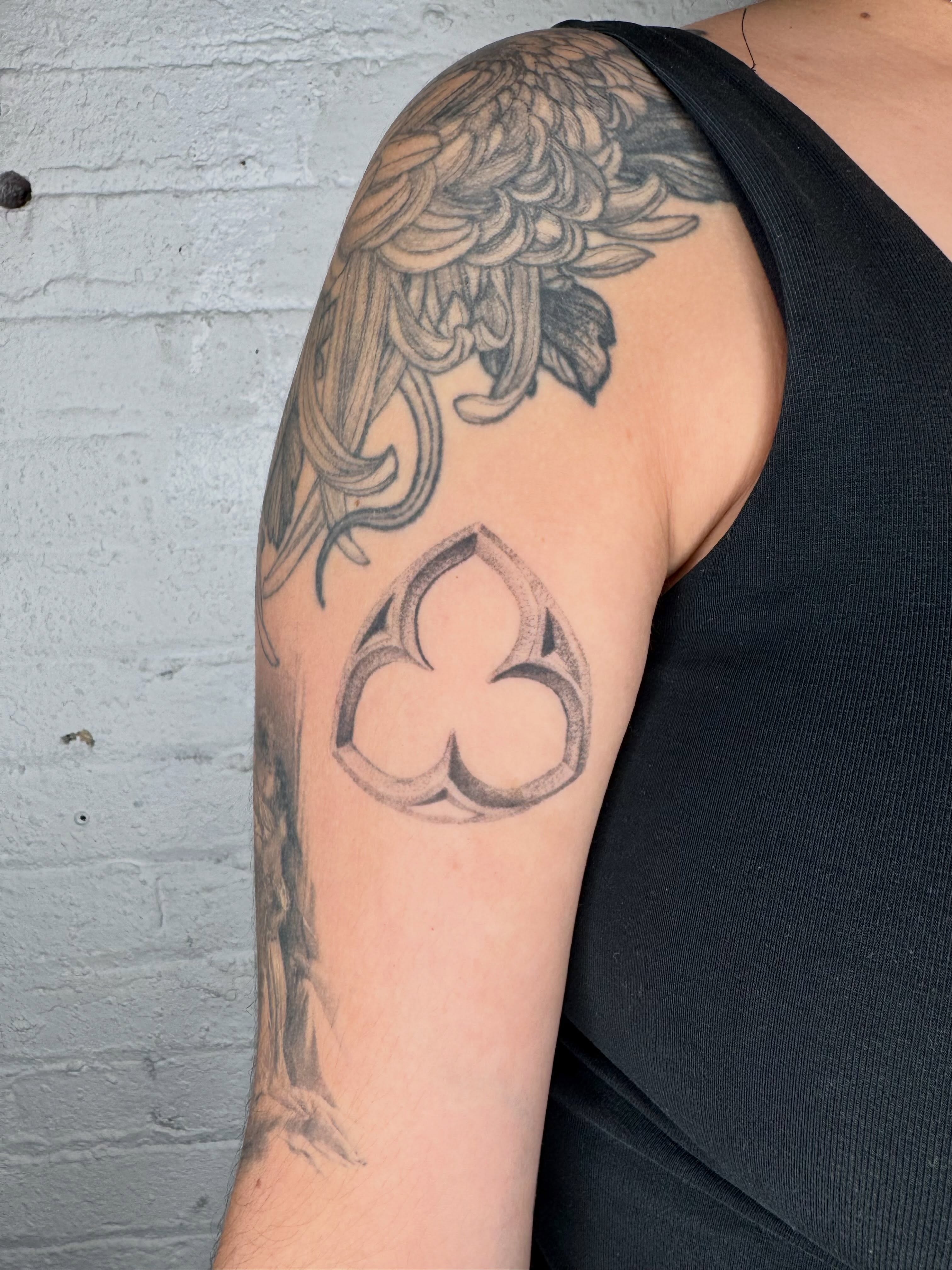 Flower and clover black and grey tattoo on the upper arm by Kenny ๐ด