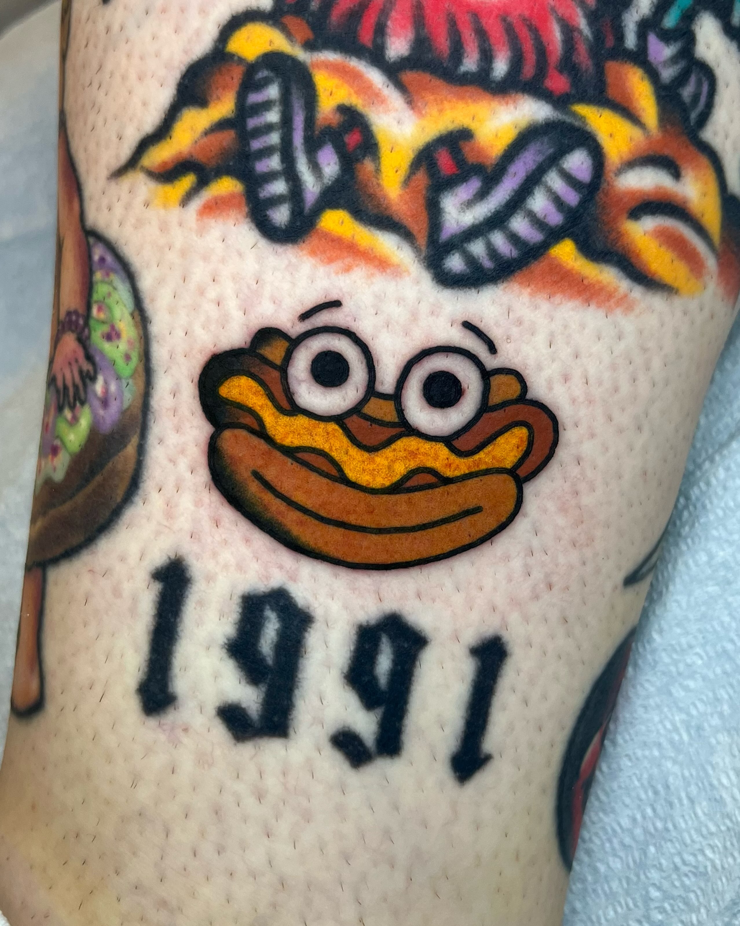 Hot dog new school tattoo on the forearm by Em Adkins