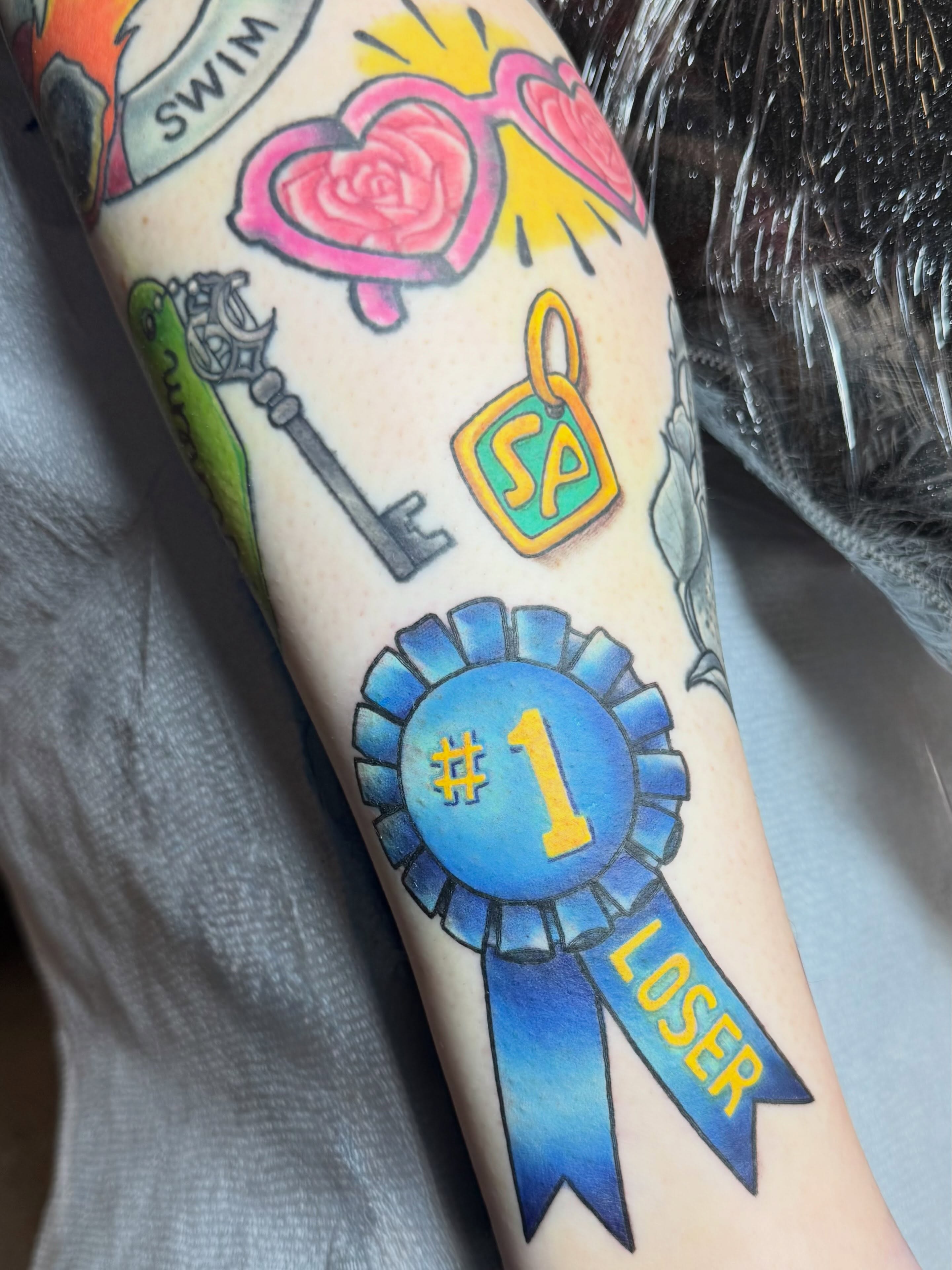 Award ribbon new school tattoo on the forearm by San Diego Tattoo Artist