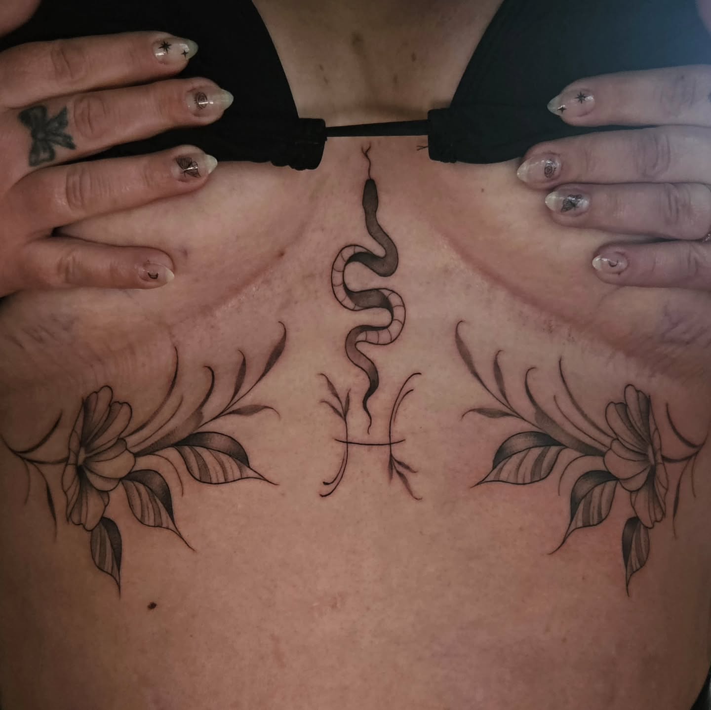 Snake and floral black and grey tattoo on the chest by Courtlyn Bliss