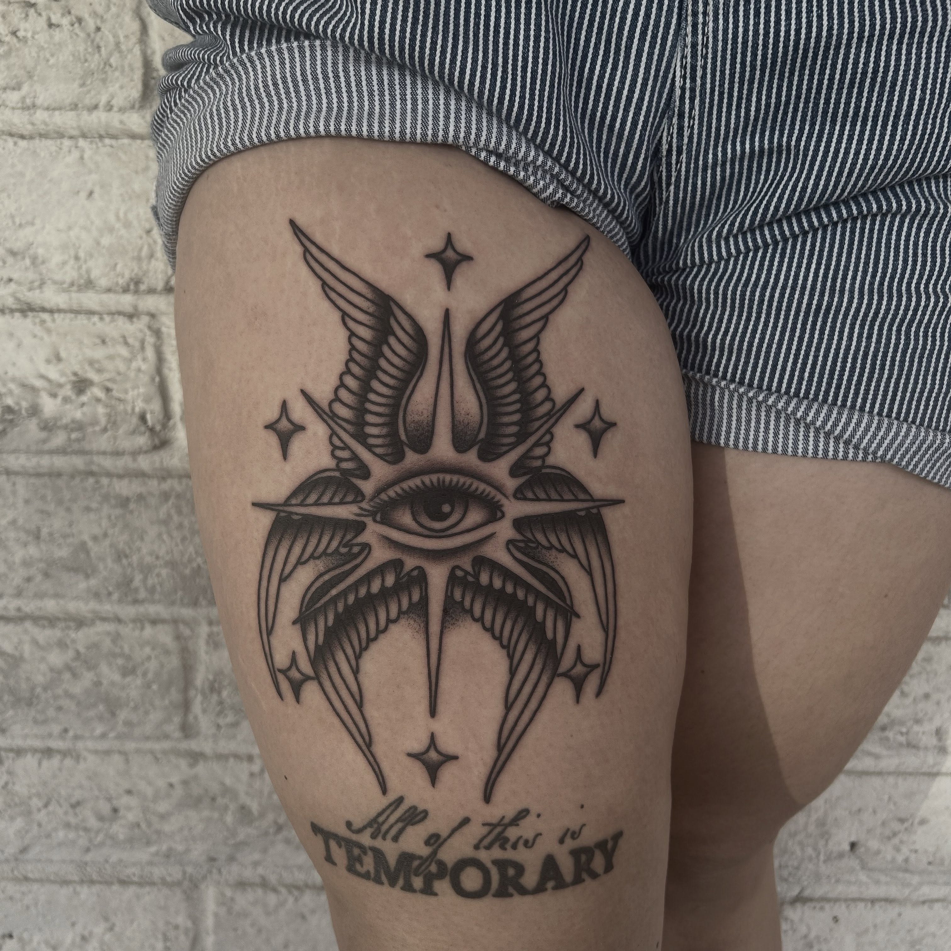 Eye with wings black and grey tattoo on the thigh by Stephen Sanchez