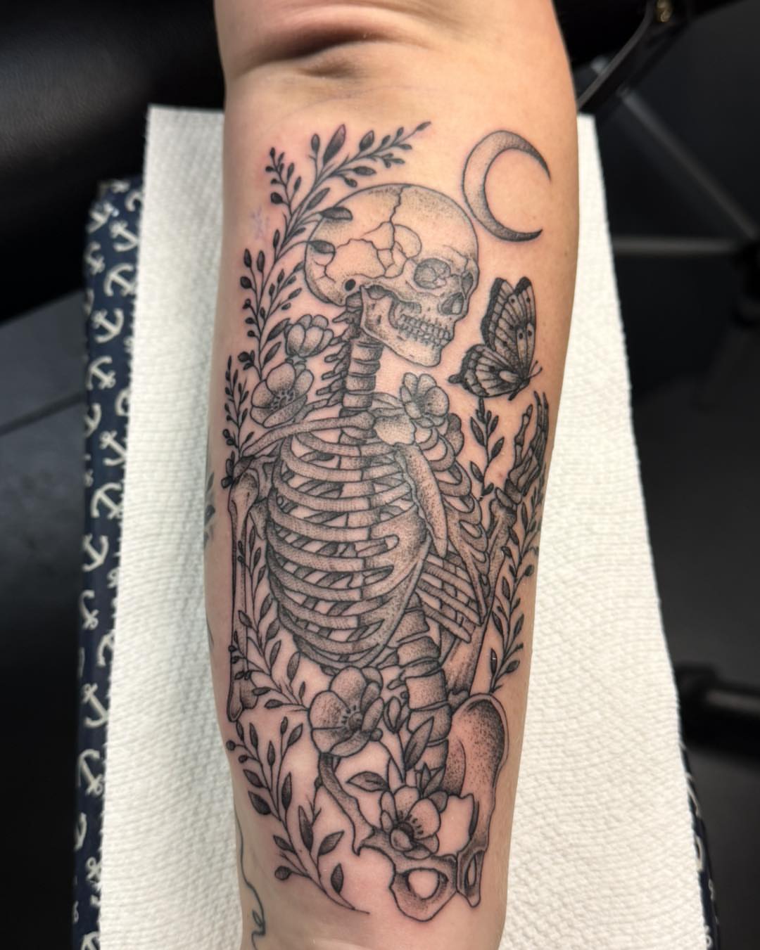 Skeleton with flowers and butterfly realism tattoo on the forearm by Bryon Smith