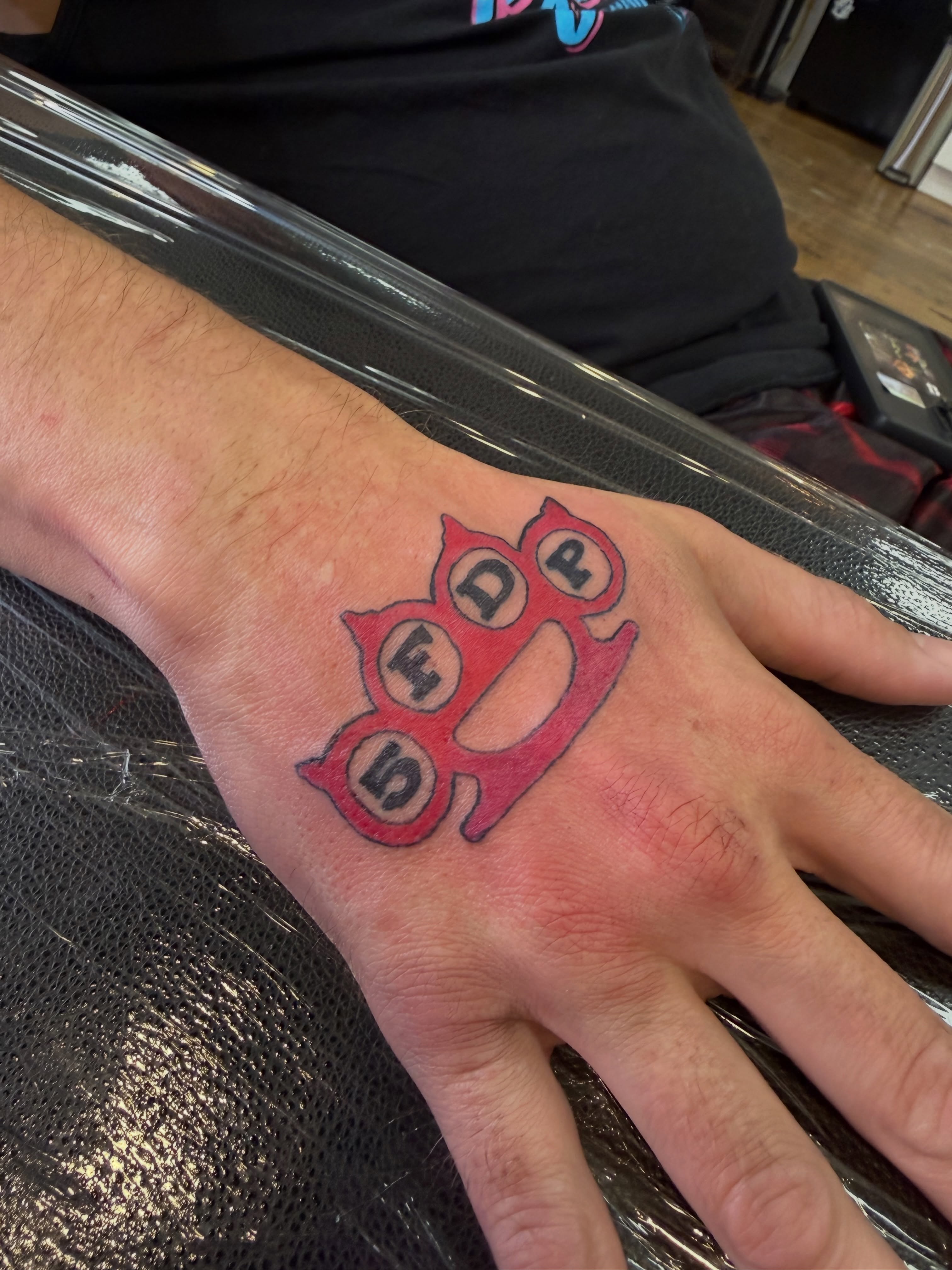 Brass knuckles American traditional tattoo on the hand by Whimsy Ink