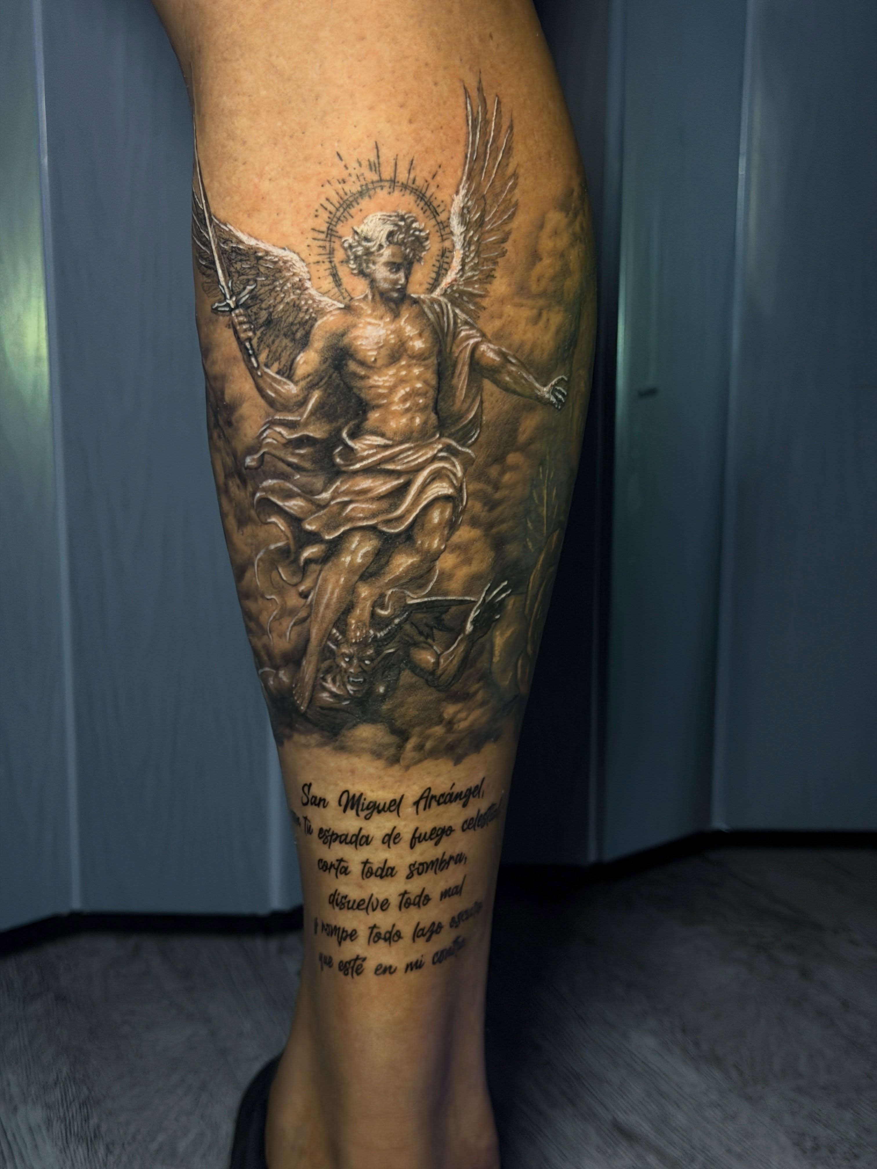 Angel slaying demon realism tattoo on the calf by Raciel Fabian Romero