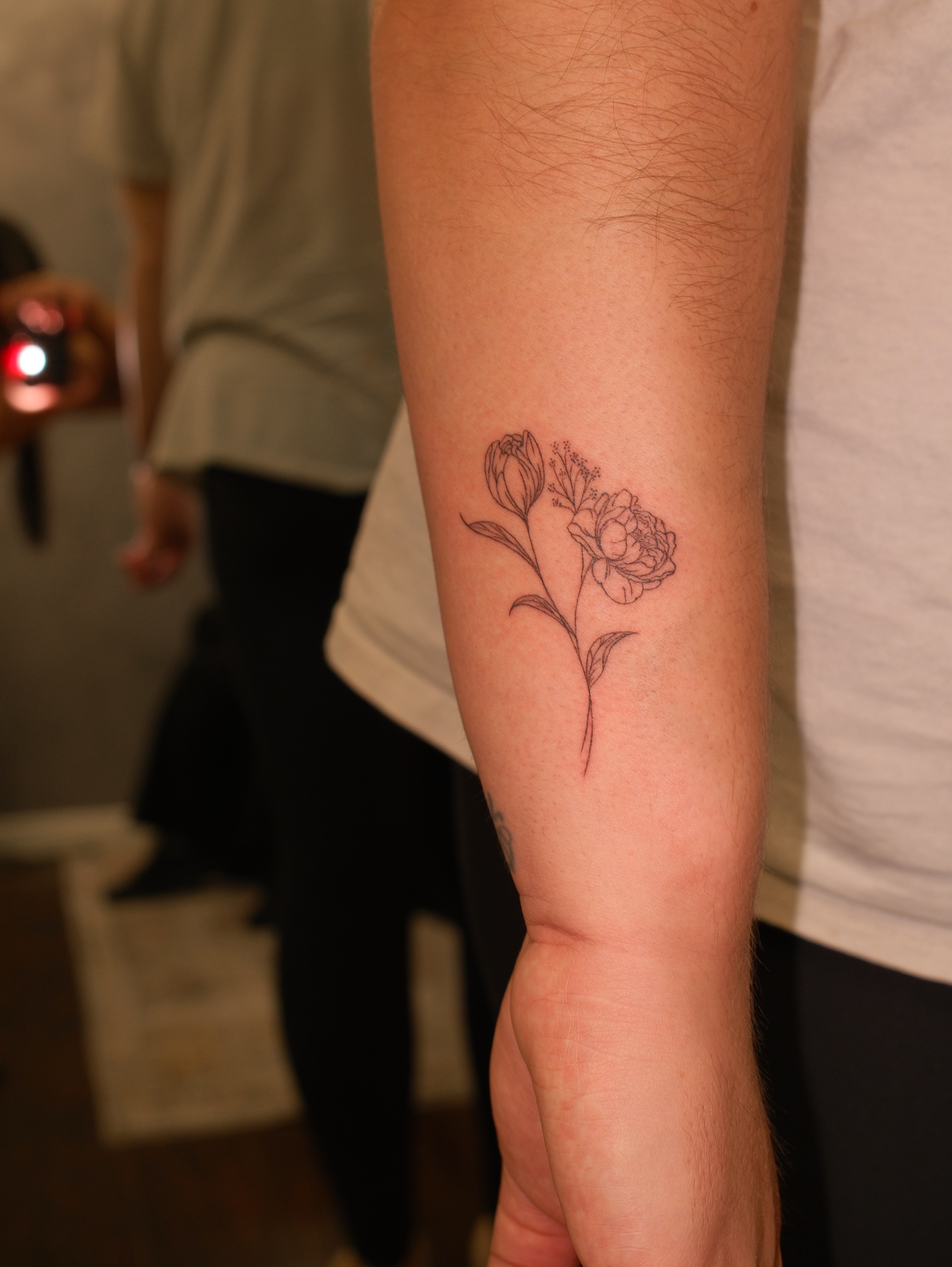 Flower fine line tattoo on the forearm by Luisa Duarte