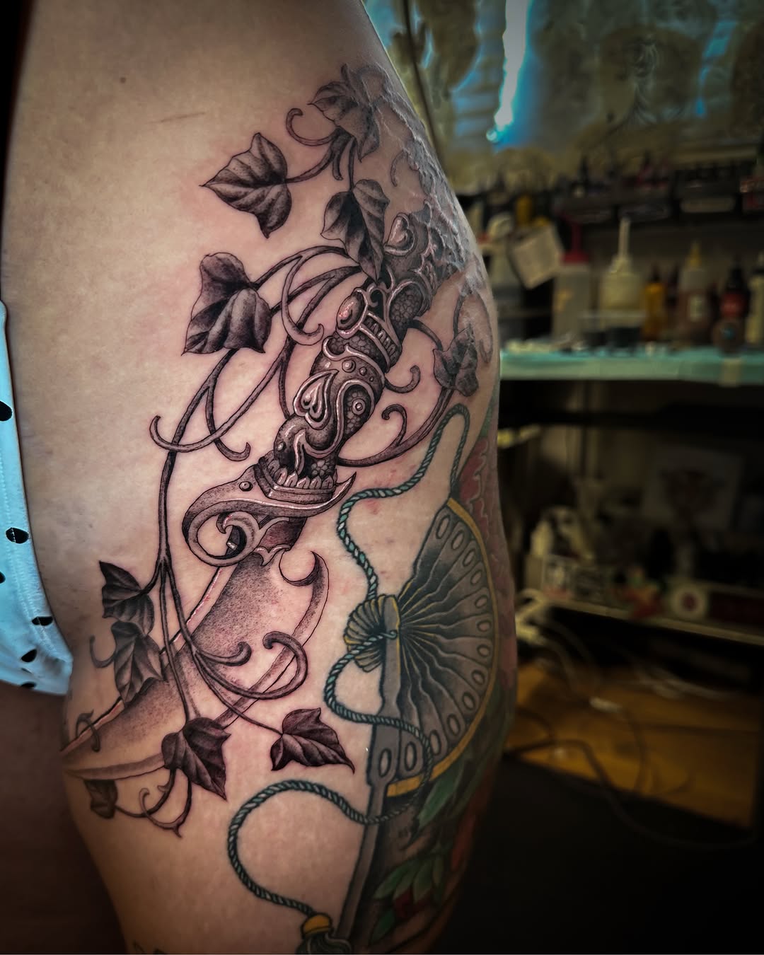 Mask and ivy ornamental tattoo on the thigh by Colin Kenji Baker, San Jose, California