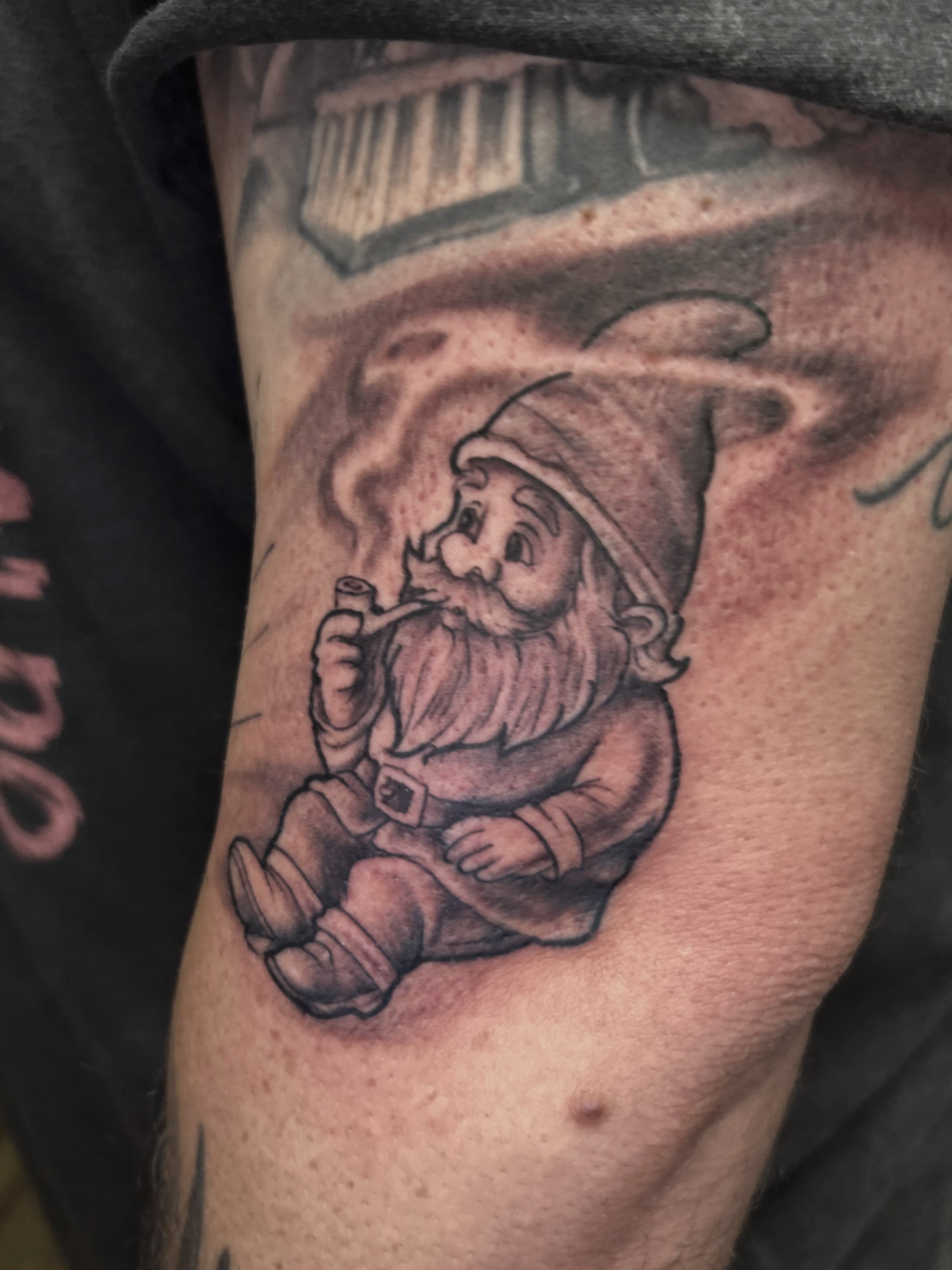 Smoking gnome black and grey tattoo on the thigh by Dan Schuster