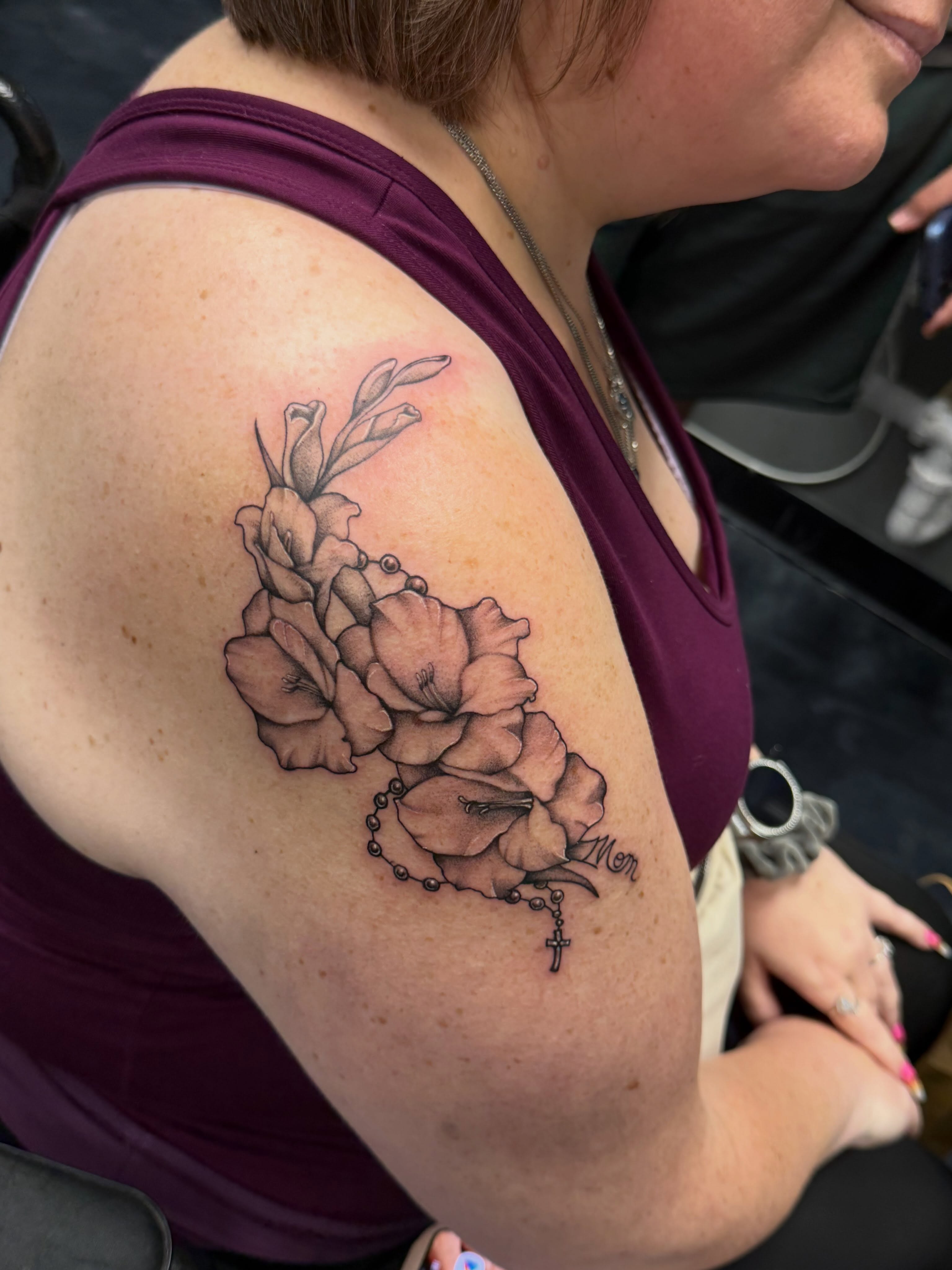 Flowers and rosary black and grey tattoo on the shoulder by Katie Rojas