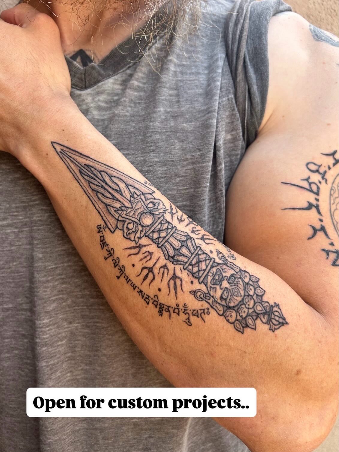 Sword and script black and grey tattoo on the forearm by Ravi Chandra, Mount Shasta, California