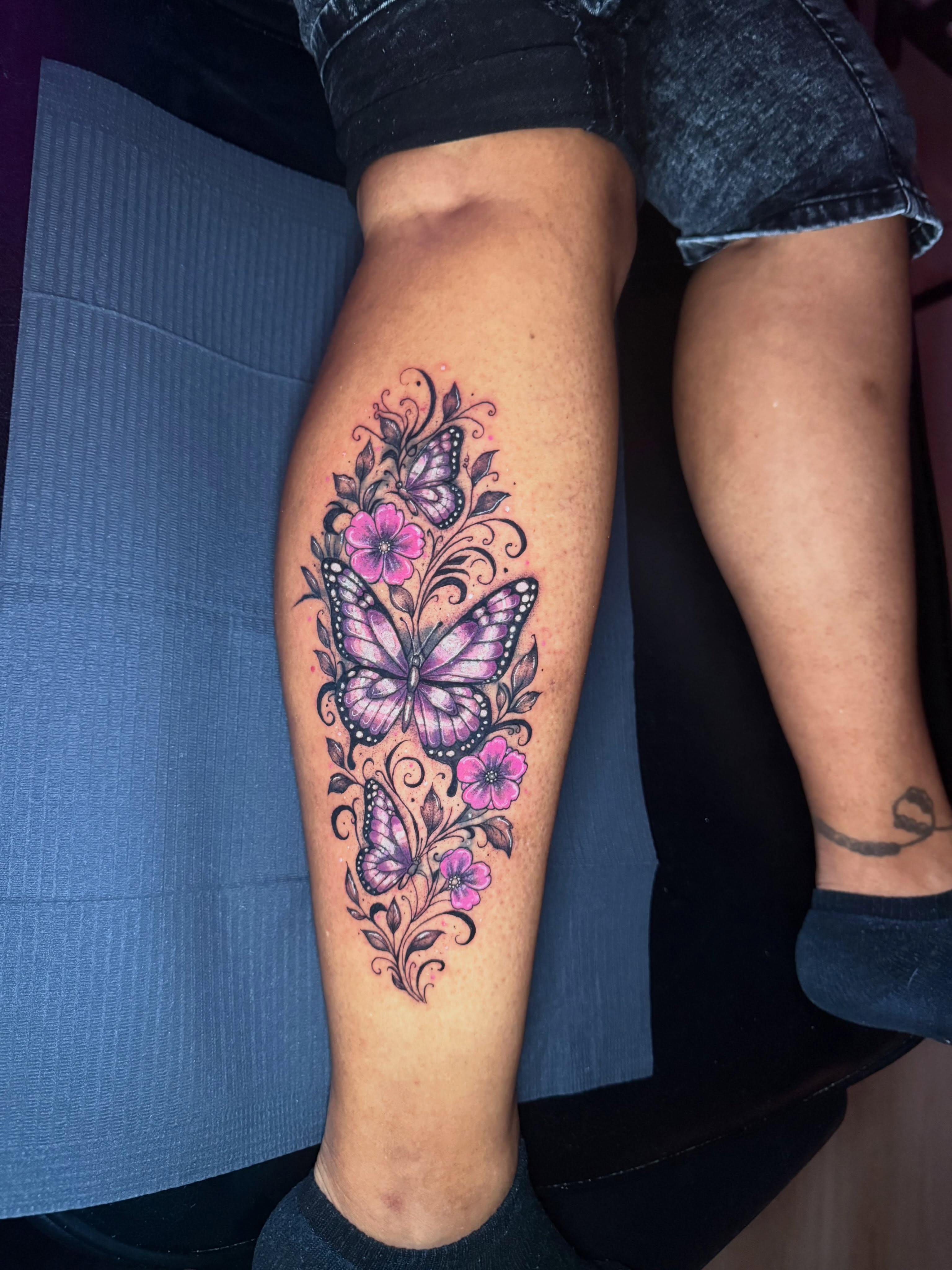 Butterfly and flowers new school tattoo on the leg by Kelsoink