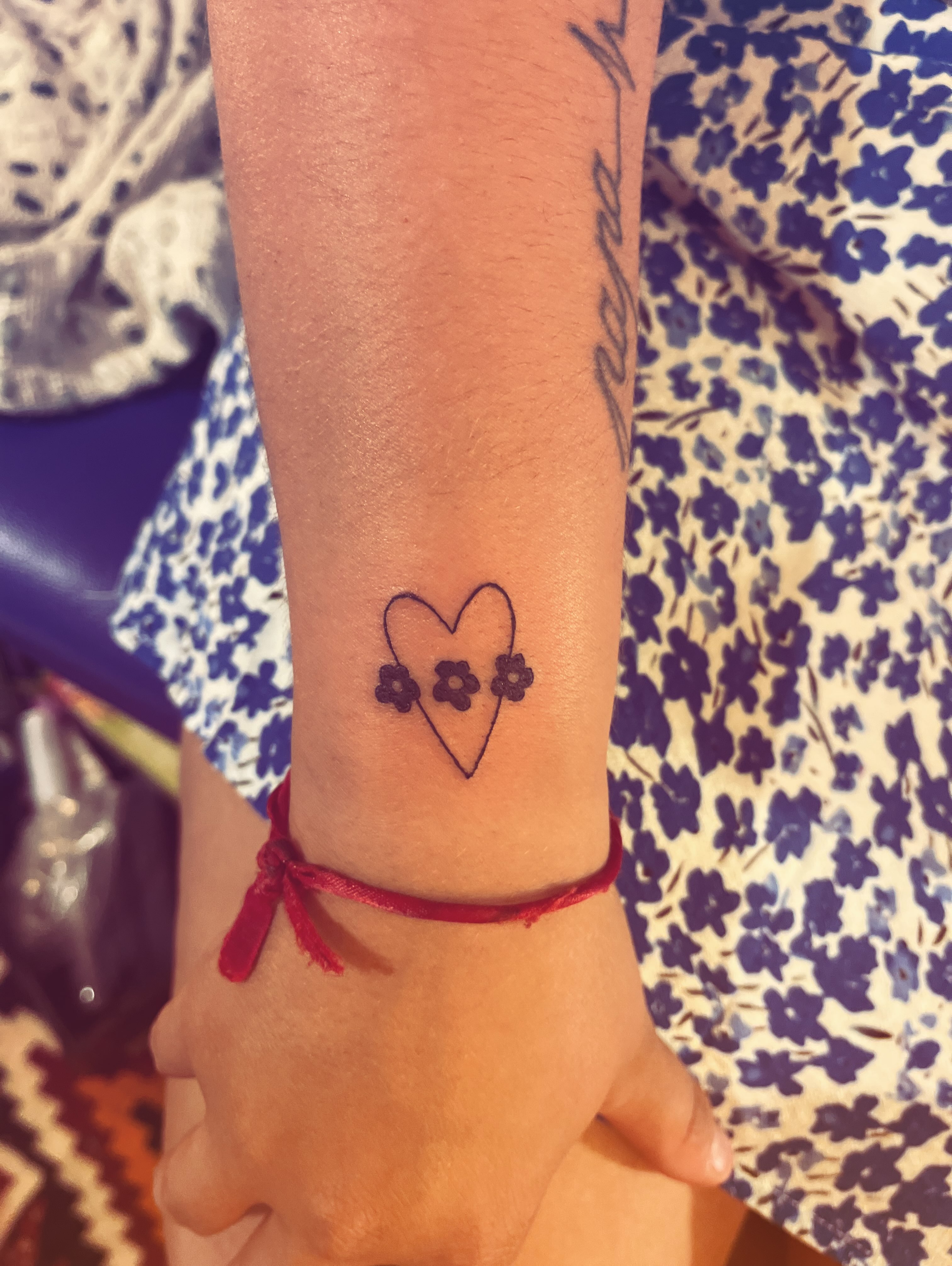 Heart with flowers minimalist tattoo on the forearm by La Main Bleue