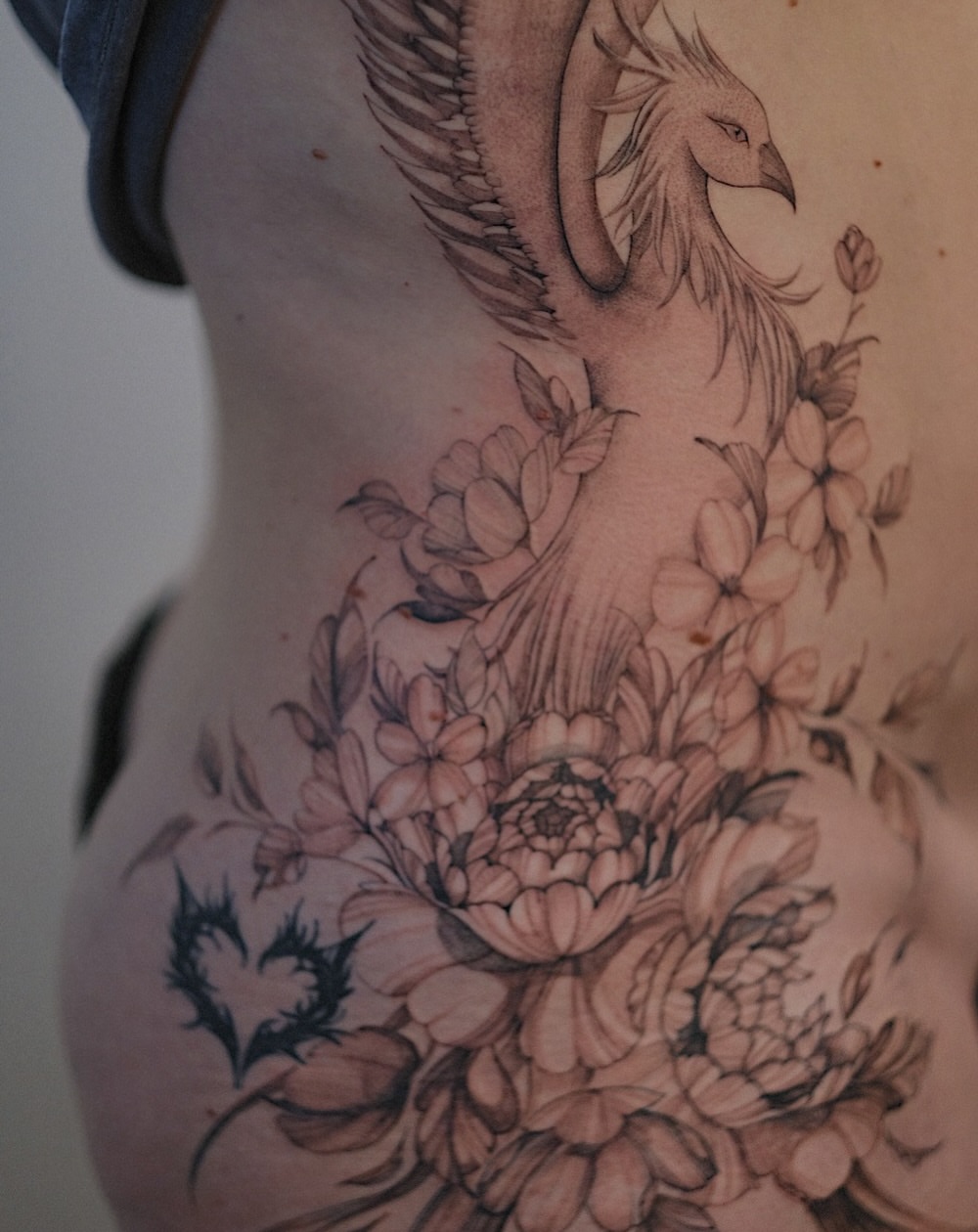 Floral phoenix realism tattoo on the ribs by Temple Adorned Tattoo