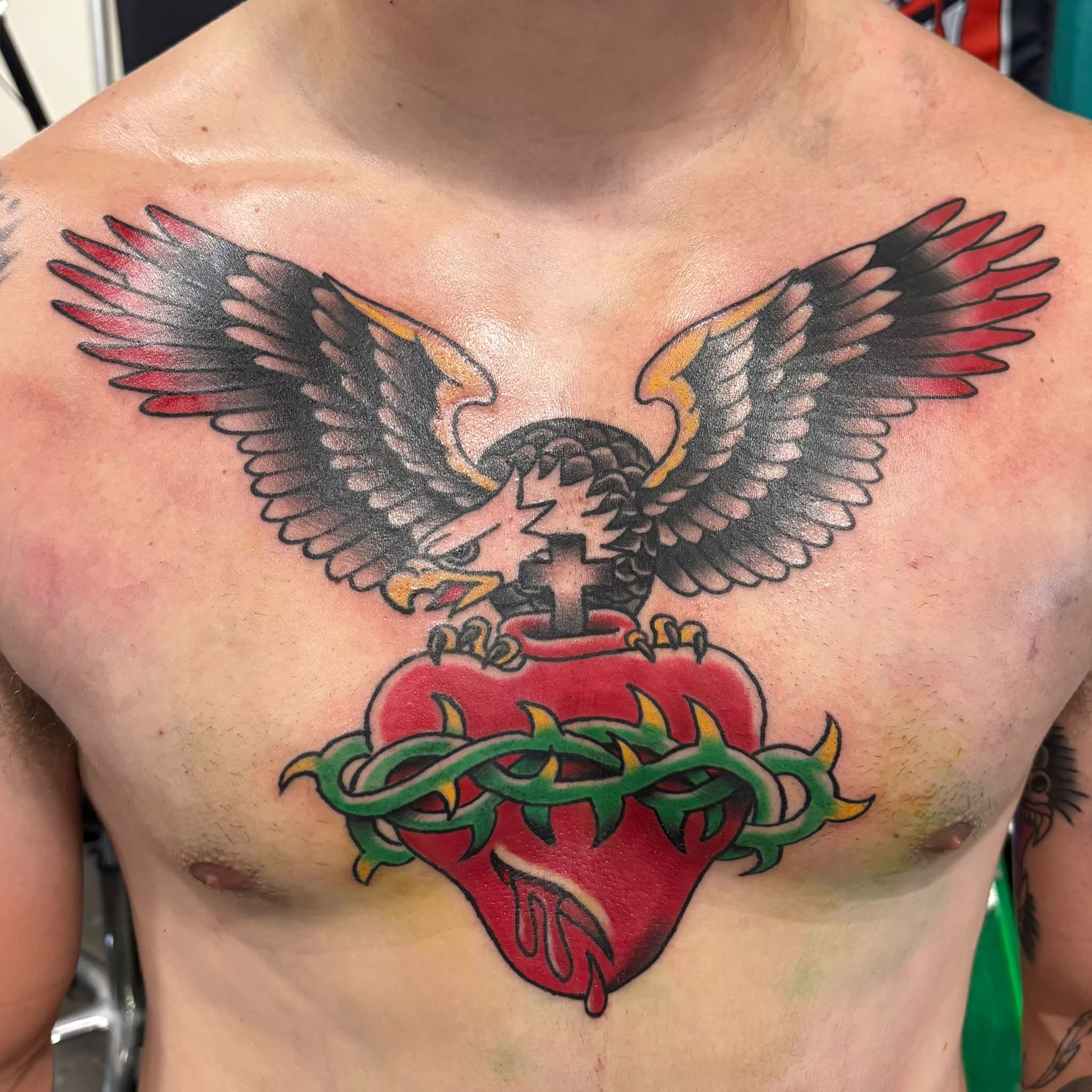 Heart with eagle American traditional tattoo on the chest by Jon Anderson
